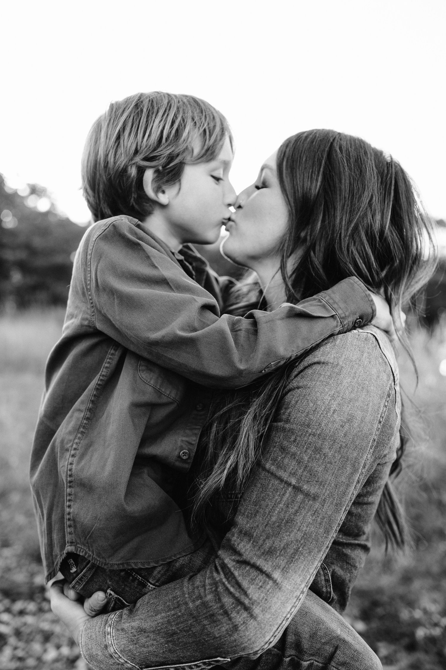 Black and white portrait showing intimate family moment outdoors.