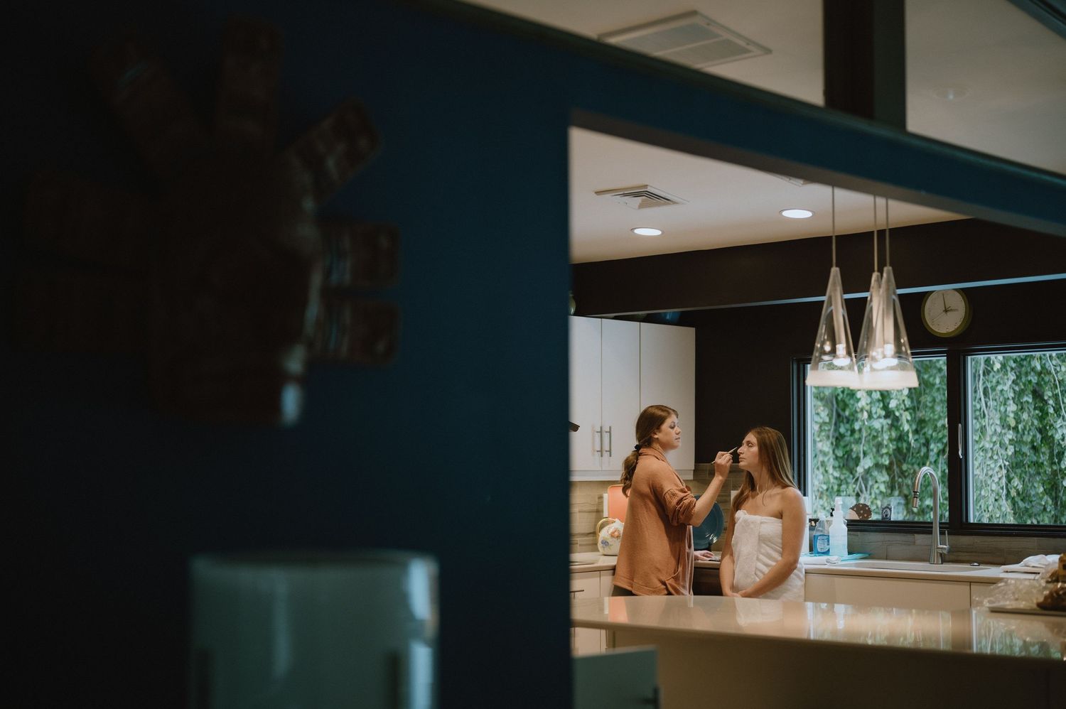 Two figures reflected in bathroom mirror with blue wall and natural lighting.