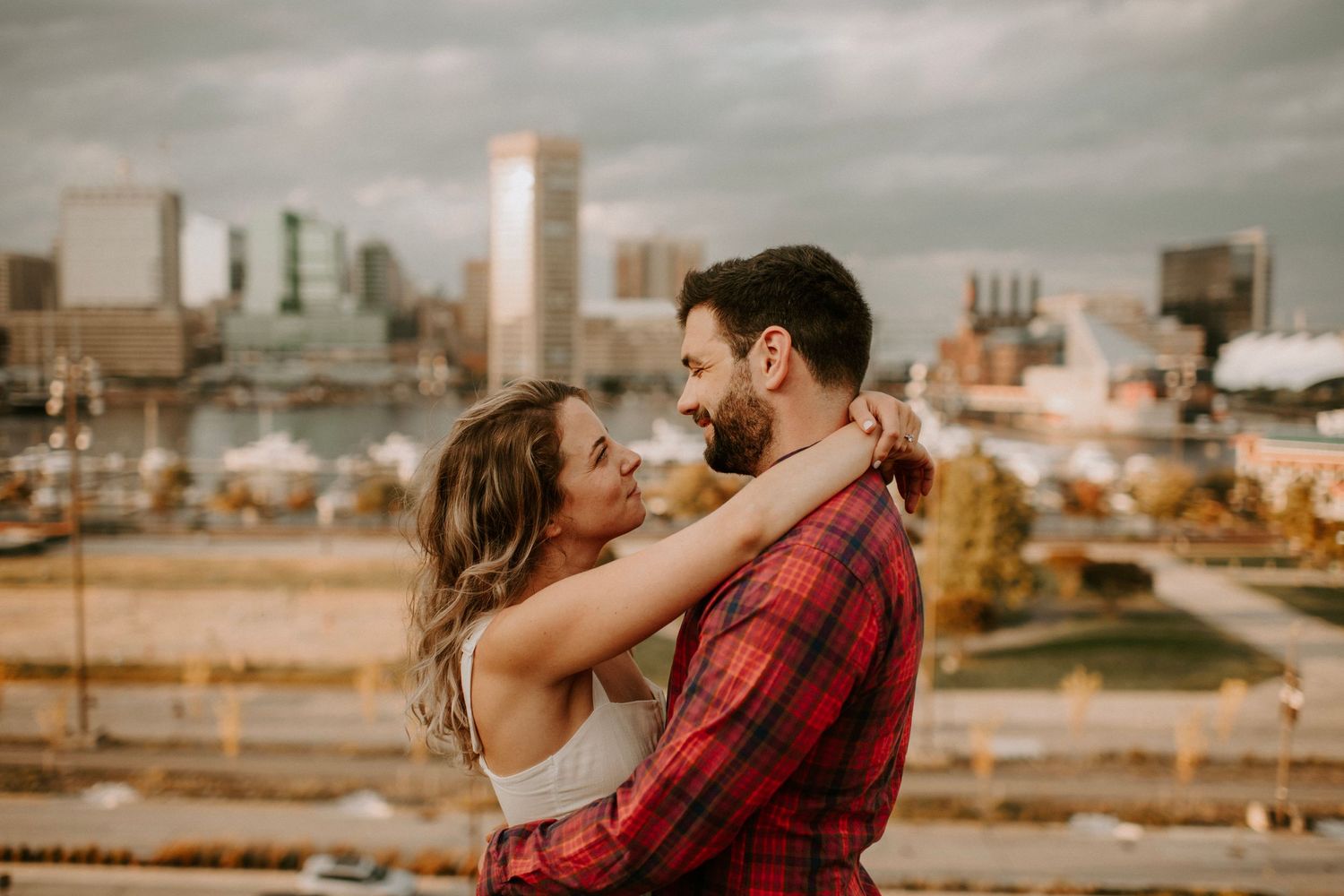 Romantic rooftop embrace against urban city skyline at sunset.