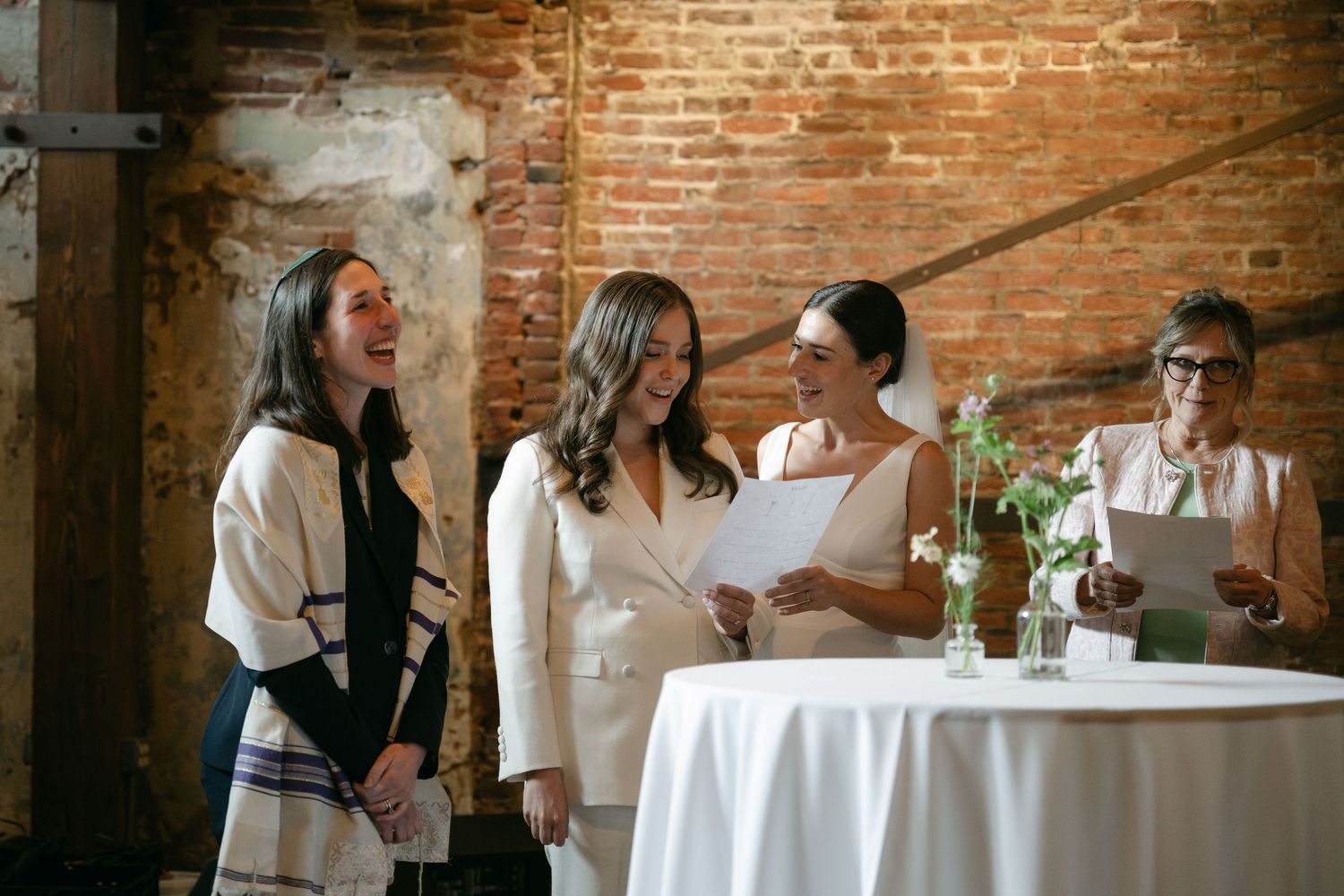 Wedding reception in a rustic brick-walled venue with elegant table settings.