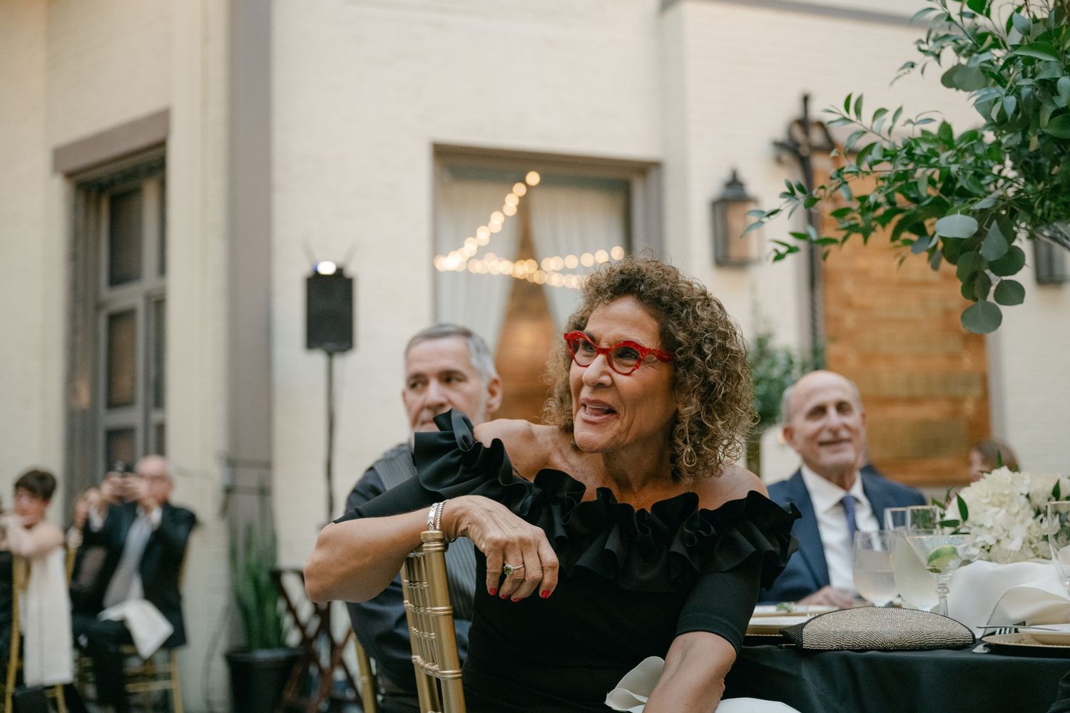 Wedding reception guests enjoying dinner and conversation at an outdoor venue.