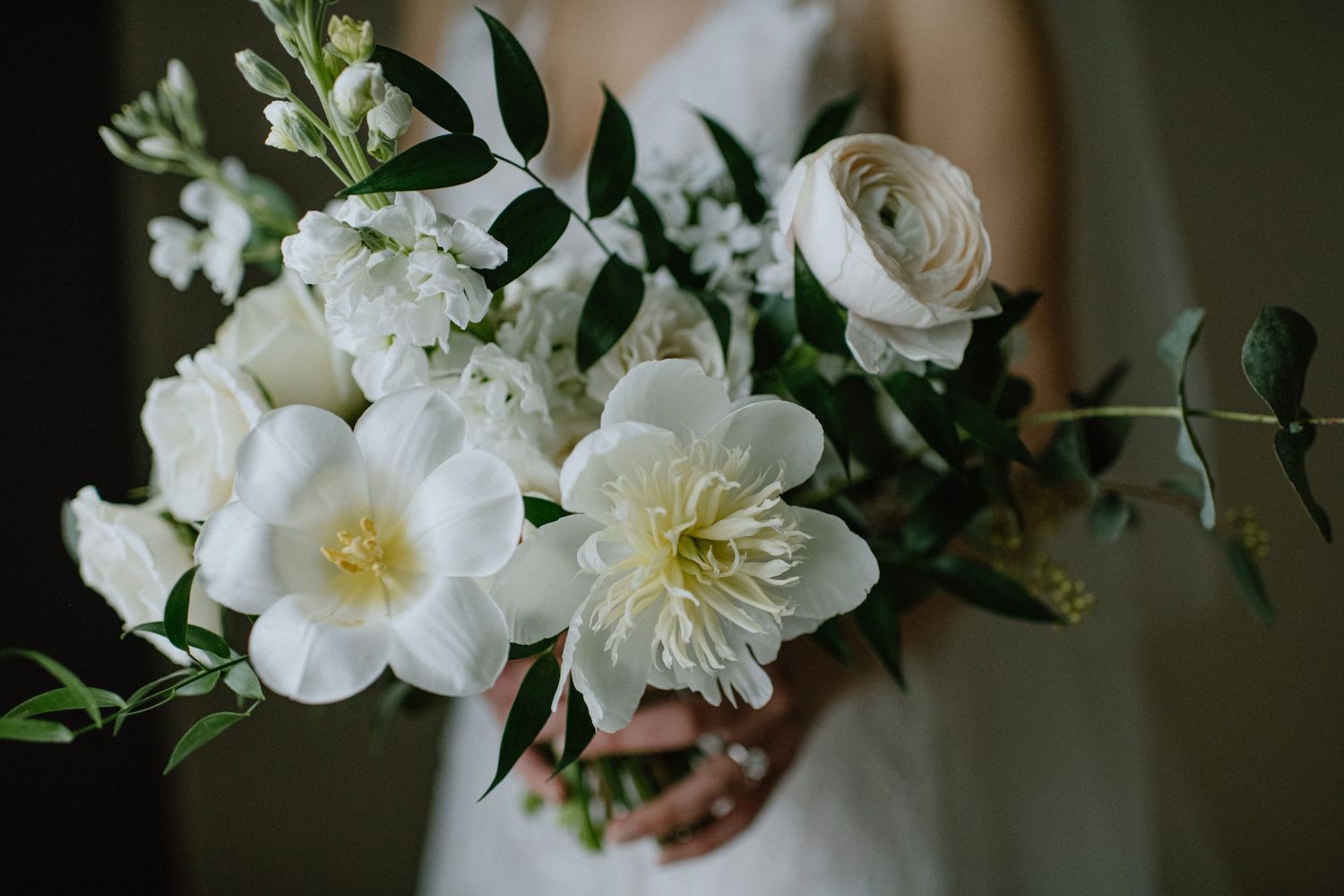 Close-up of white floral wedding arrangement with roses and greenery.