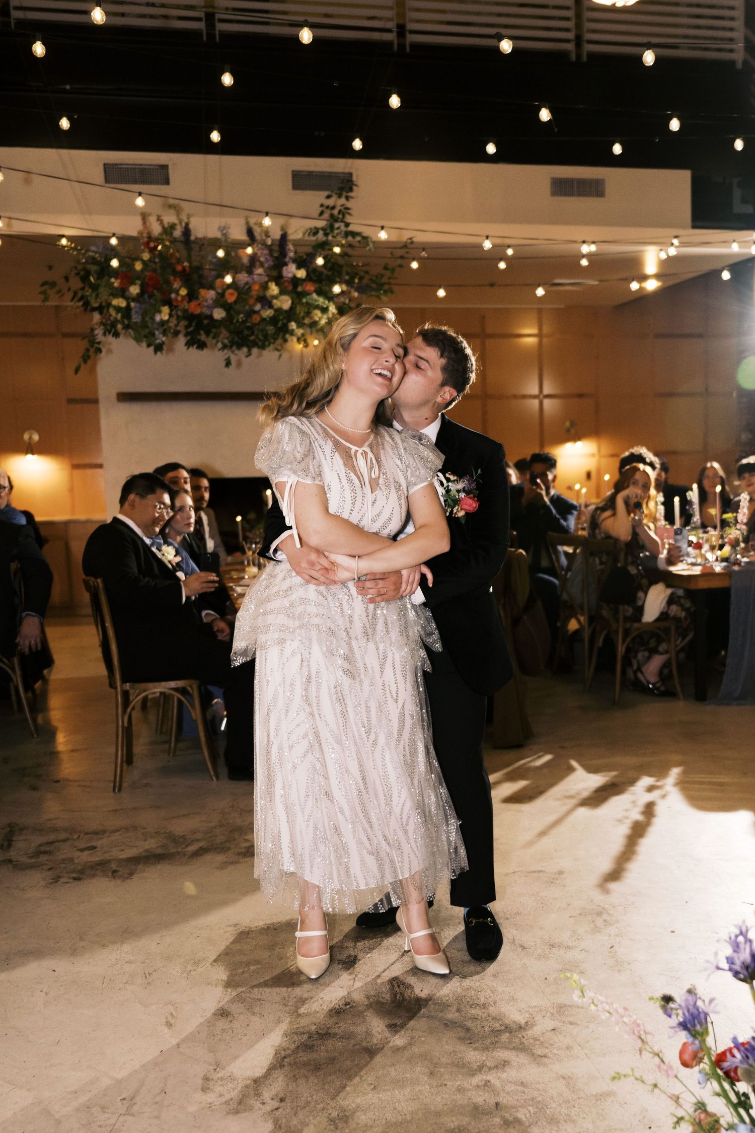 Wedding couple sharing an intimate dance moment under string lights at their reception.