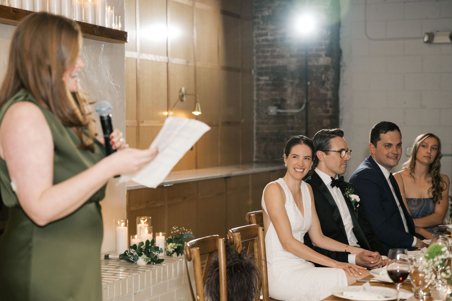 Wedding guests listen intently during a dinner reception speech.