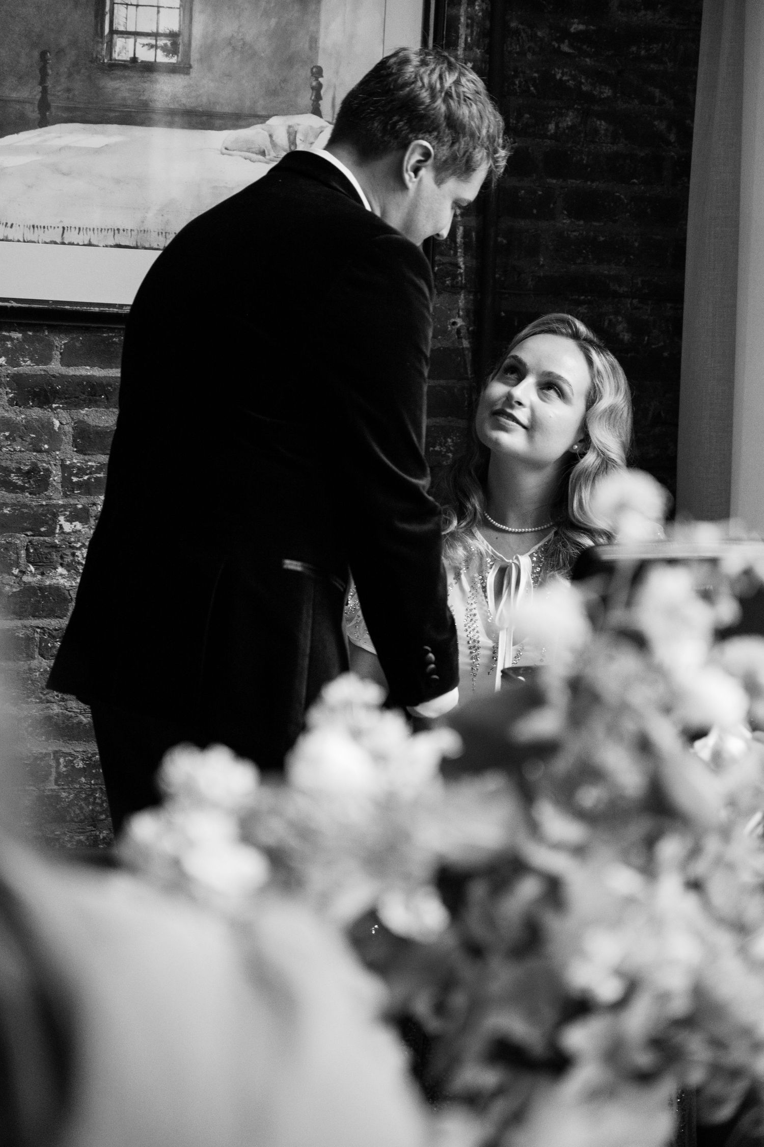 A romantic black and white moment between two people with flowers in the foreground.