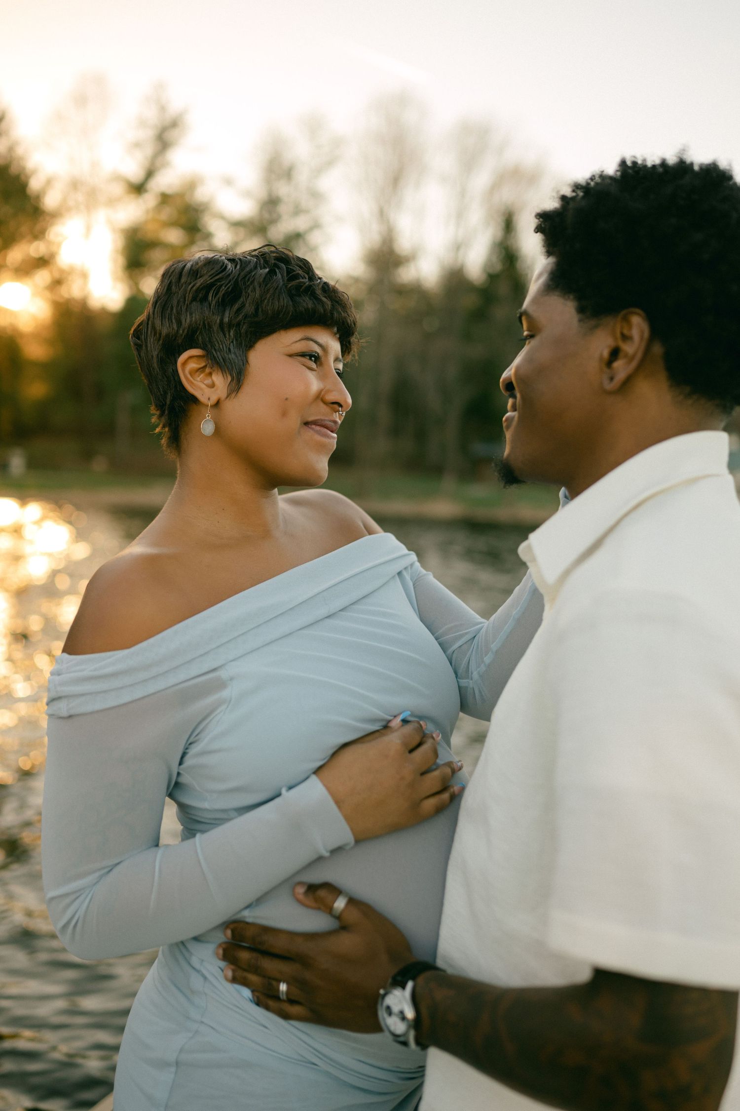 pregnant woman smiles at man with water glistening in background