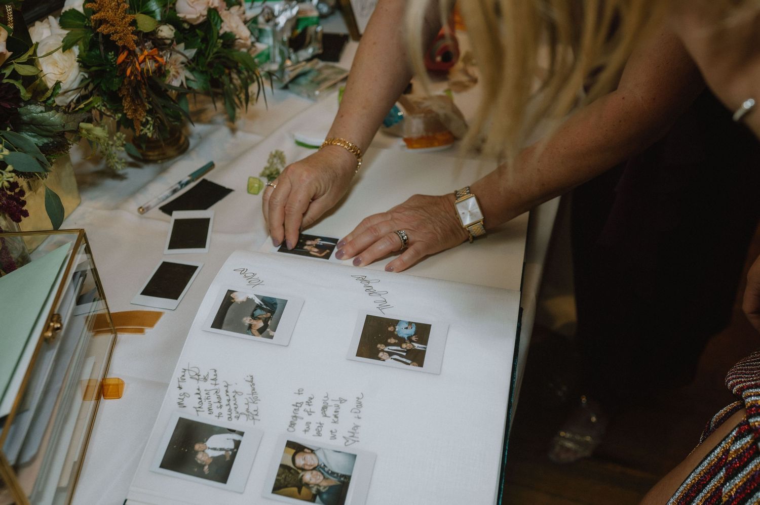Guests sign a wedding guestbook featuring polaroid photos and handwritten messages.