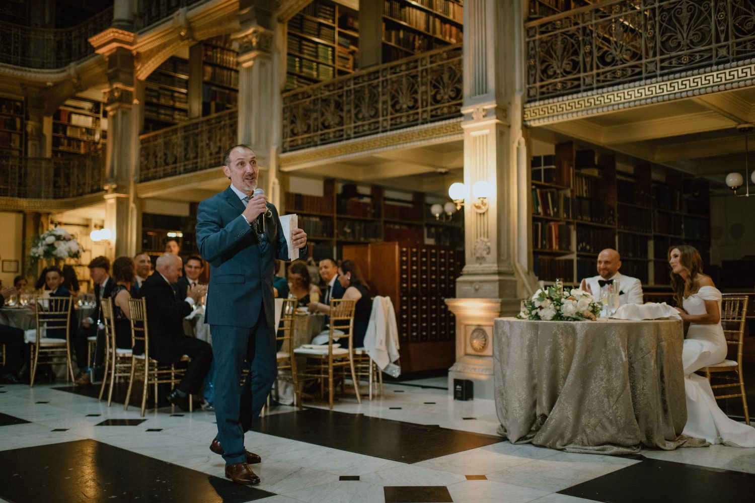 Wedding speech in an elegant library venue with ornate architecture and ambient lighting.