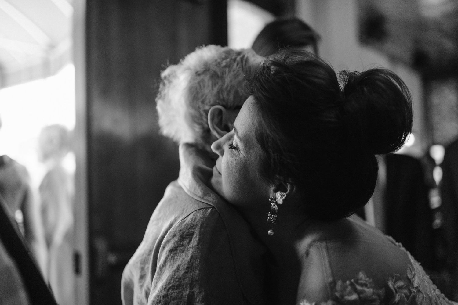 An intimate black and white moment shared between wedding guests during a celebration.