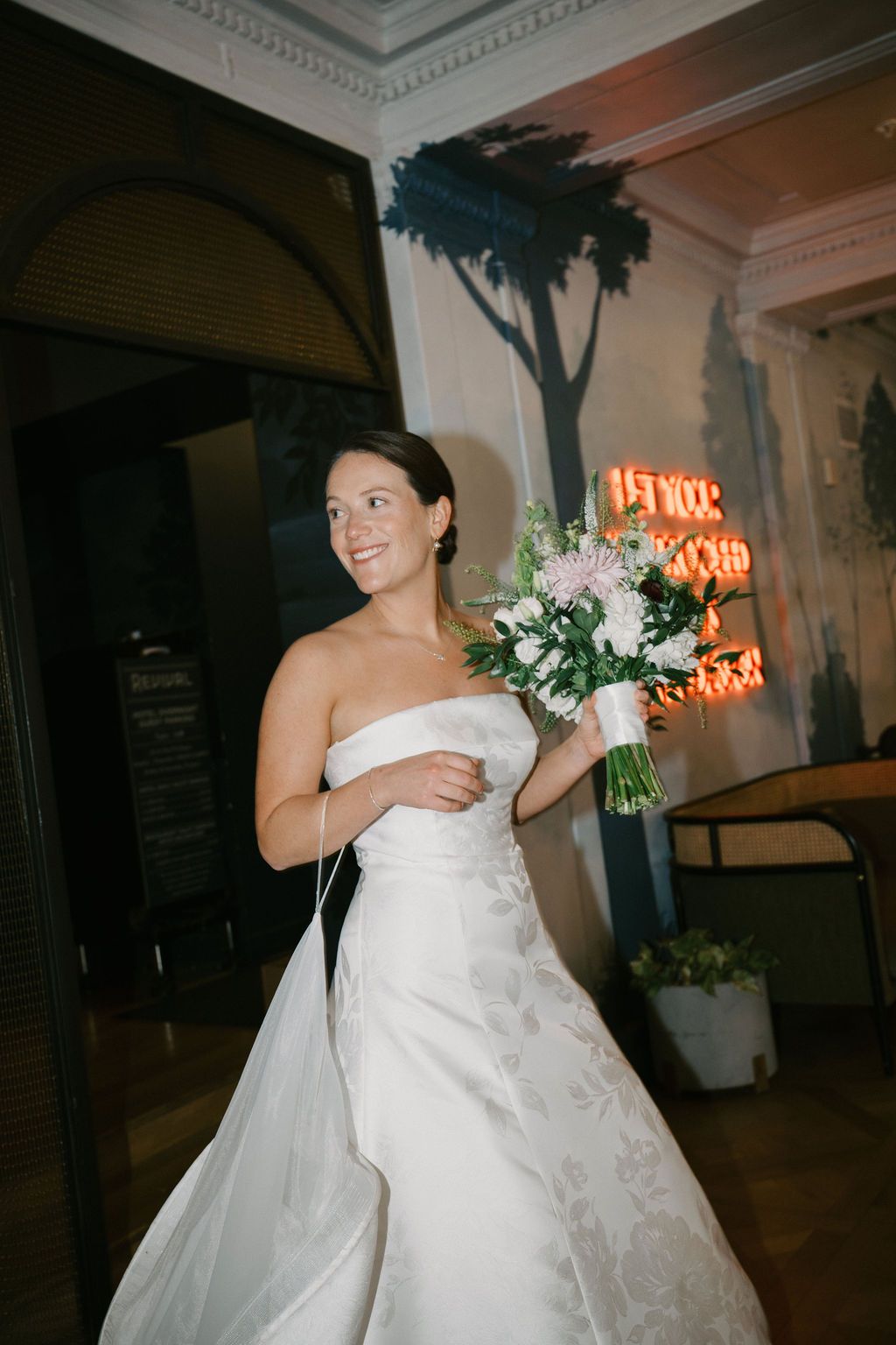 Bride in a white wedding gown dancing and celebrating at an evening reception venue.