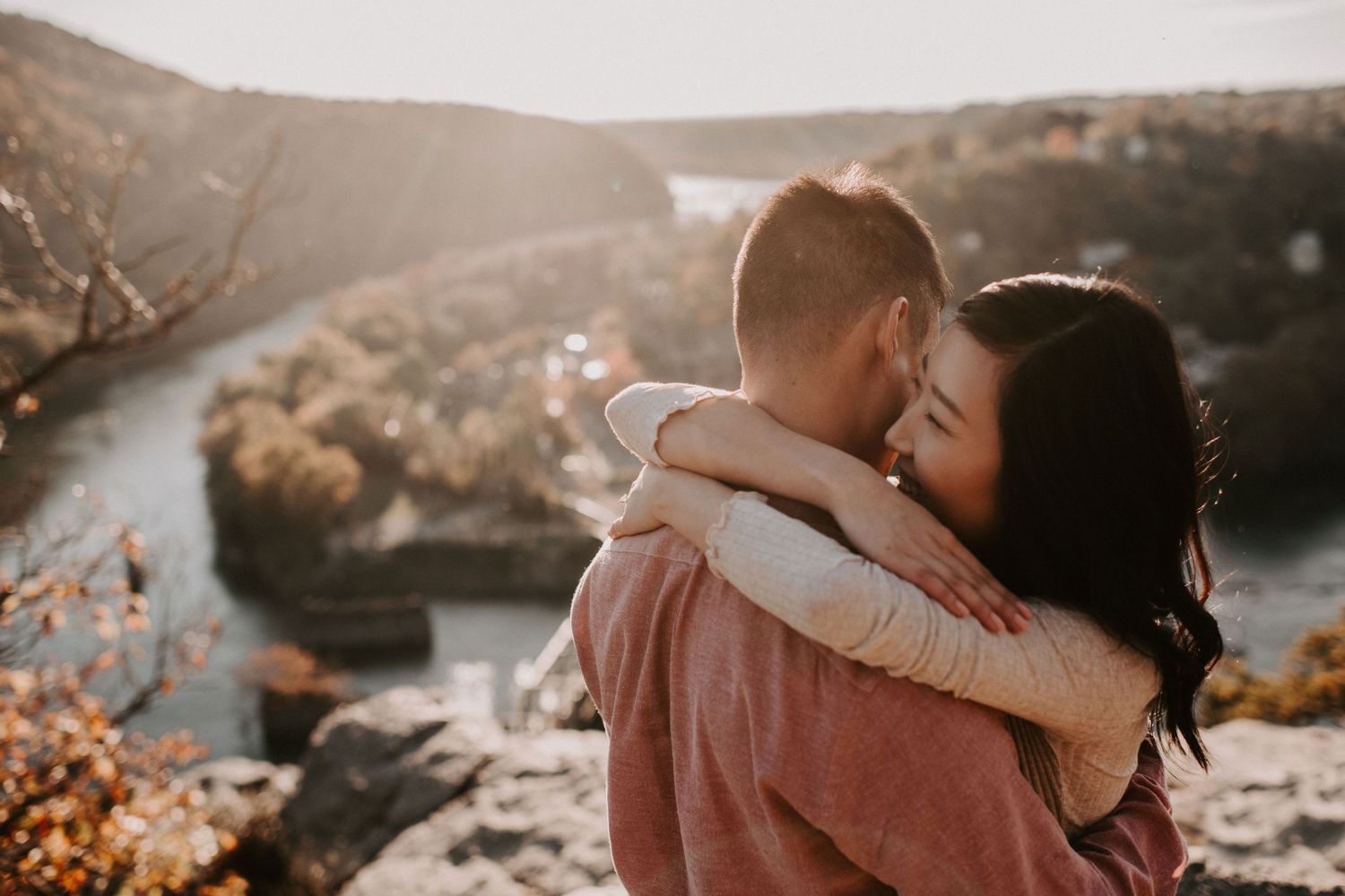 A romantic embrace overlooking a scenic river valley during autumn.