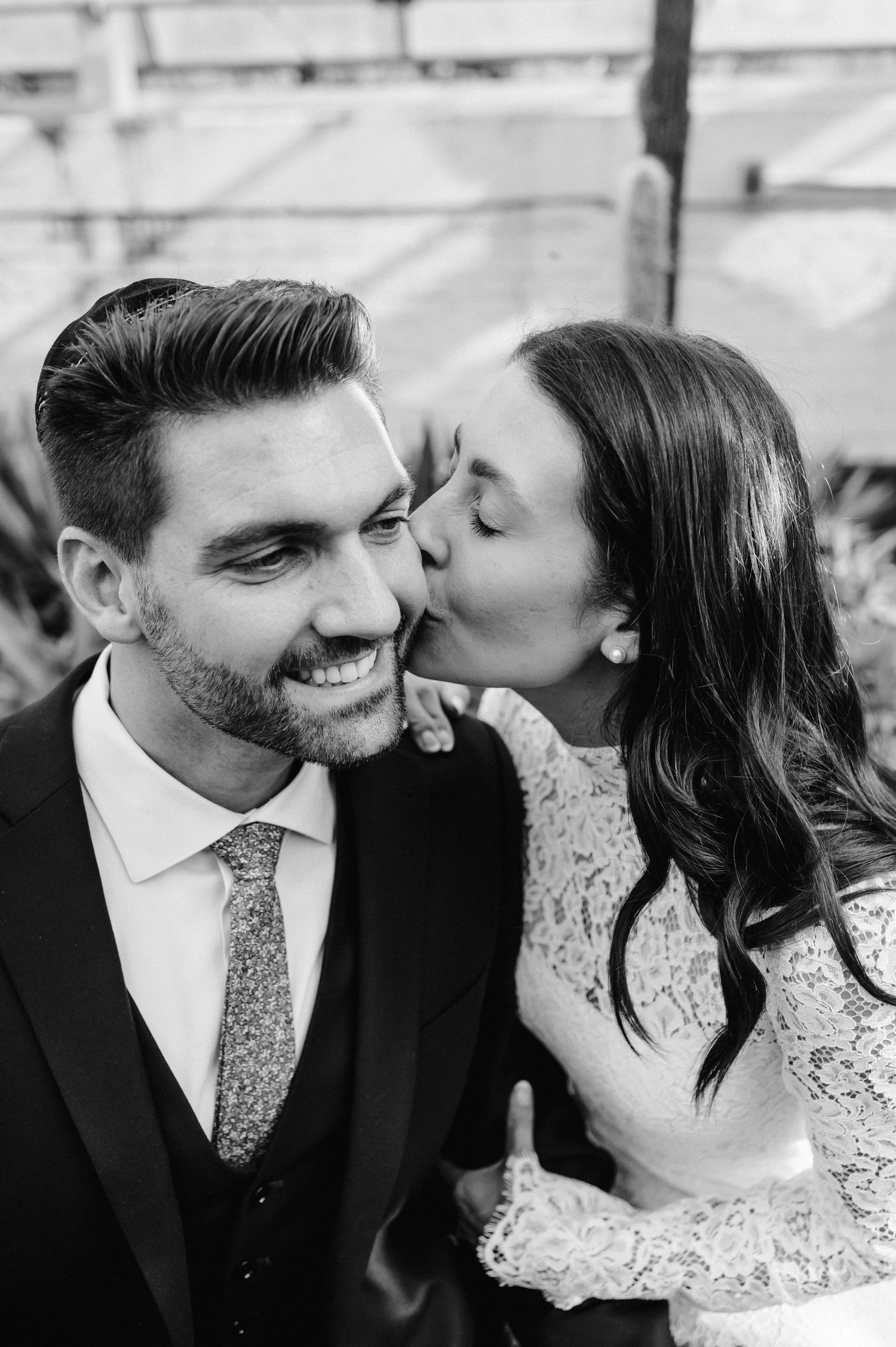 A romantic black and white portrait of a couple sharing an intimate moment with the bride kissing the groom's cheek.