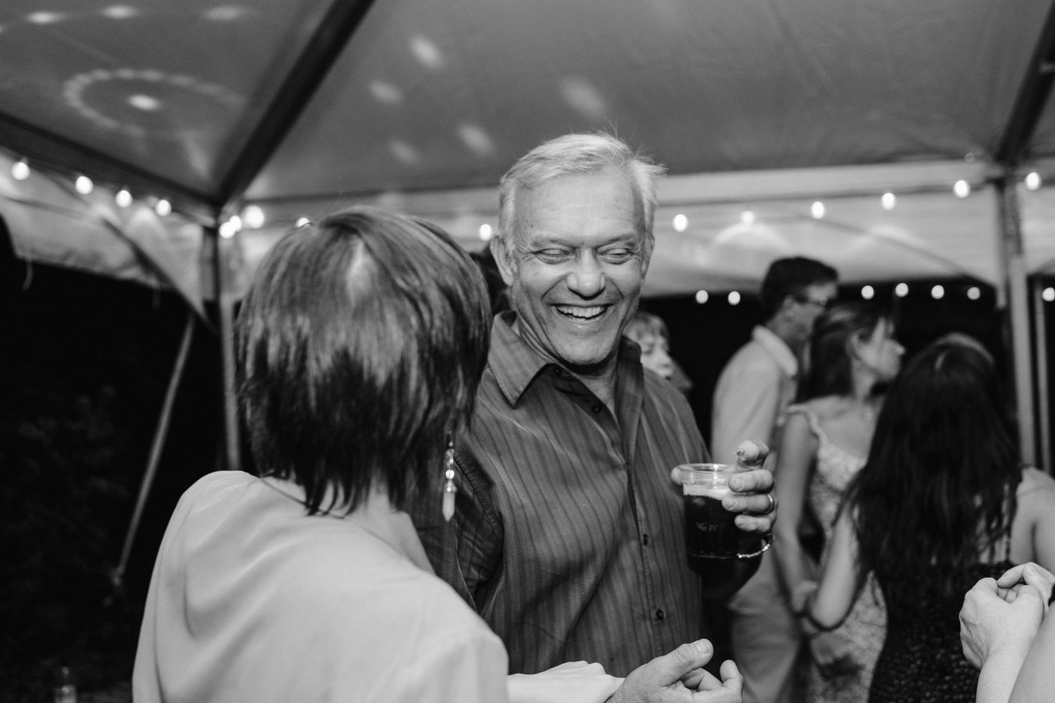 Black and white photo of guests chatting and enjoying refreshments at a party.