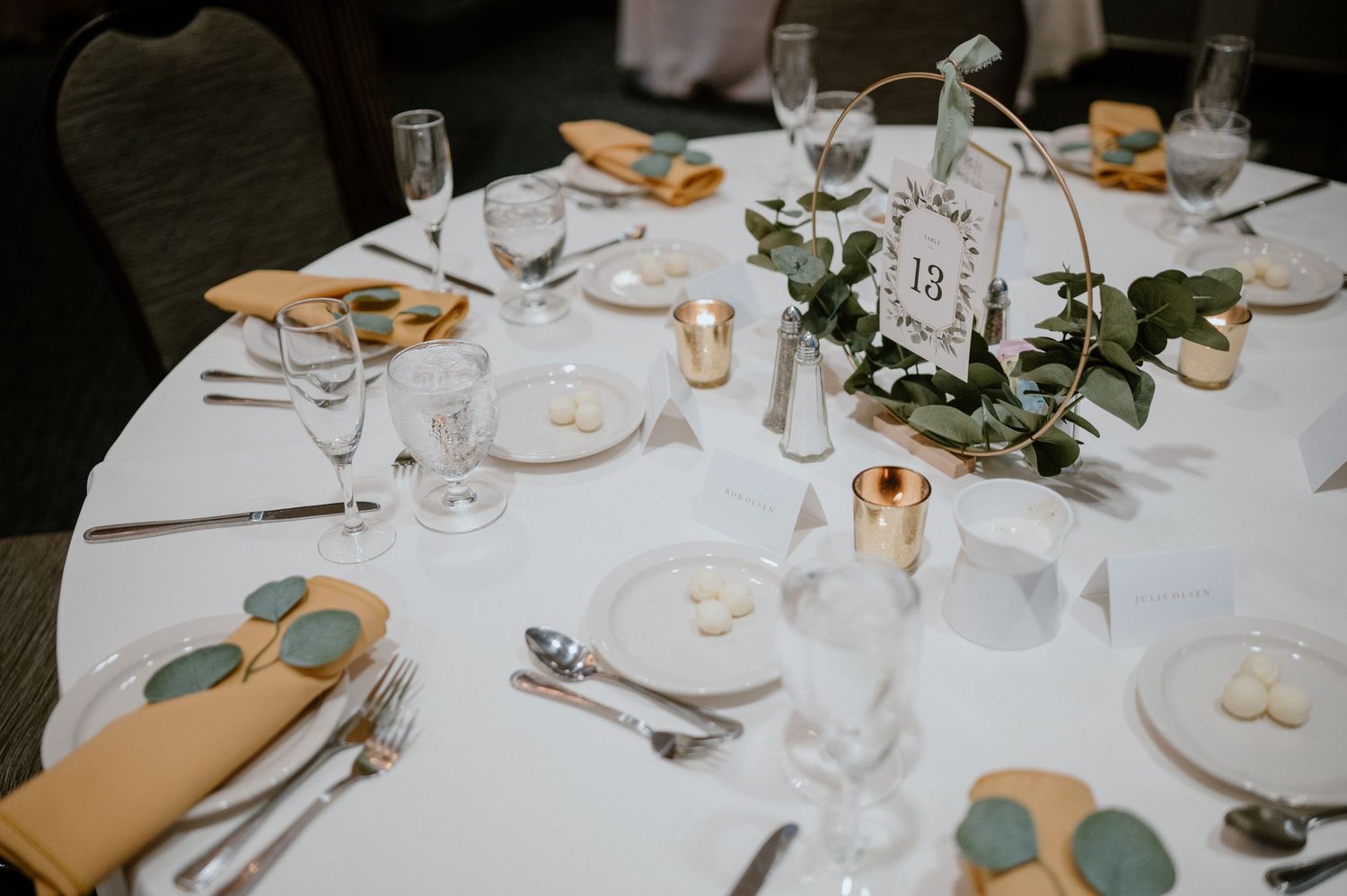 A formal place setting at a wedding reception with glassware, plates and floral centerpiece.