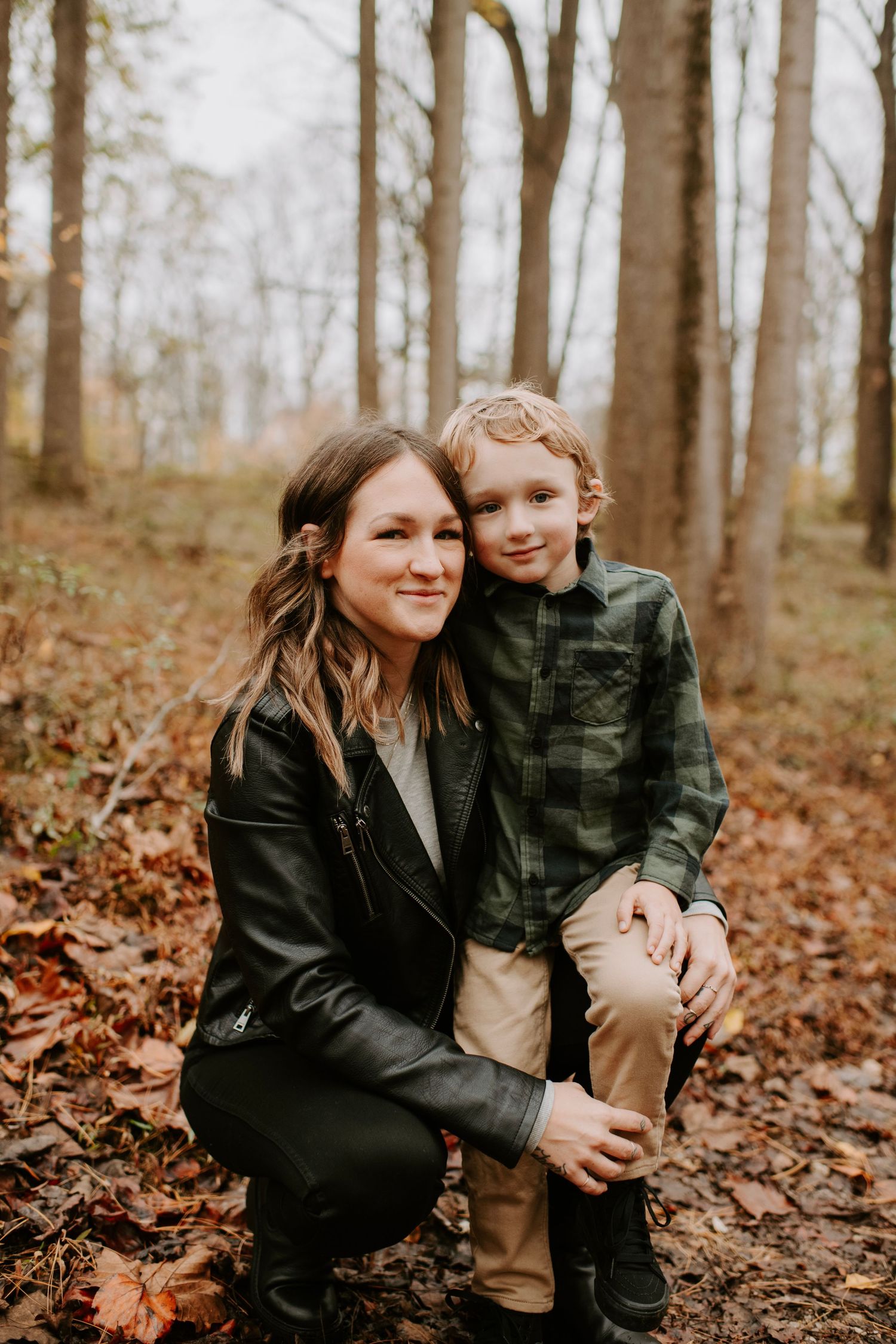 Intimate portrait in autumn forest with fallen leaves.