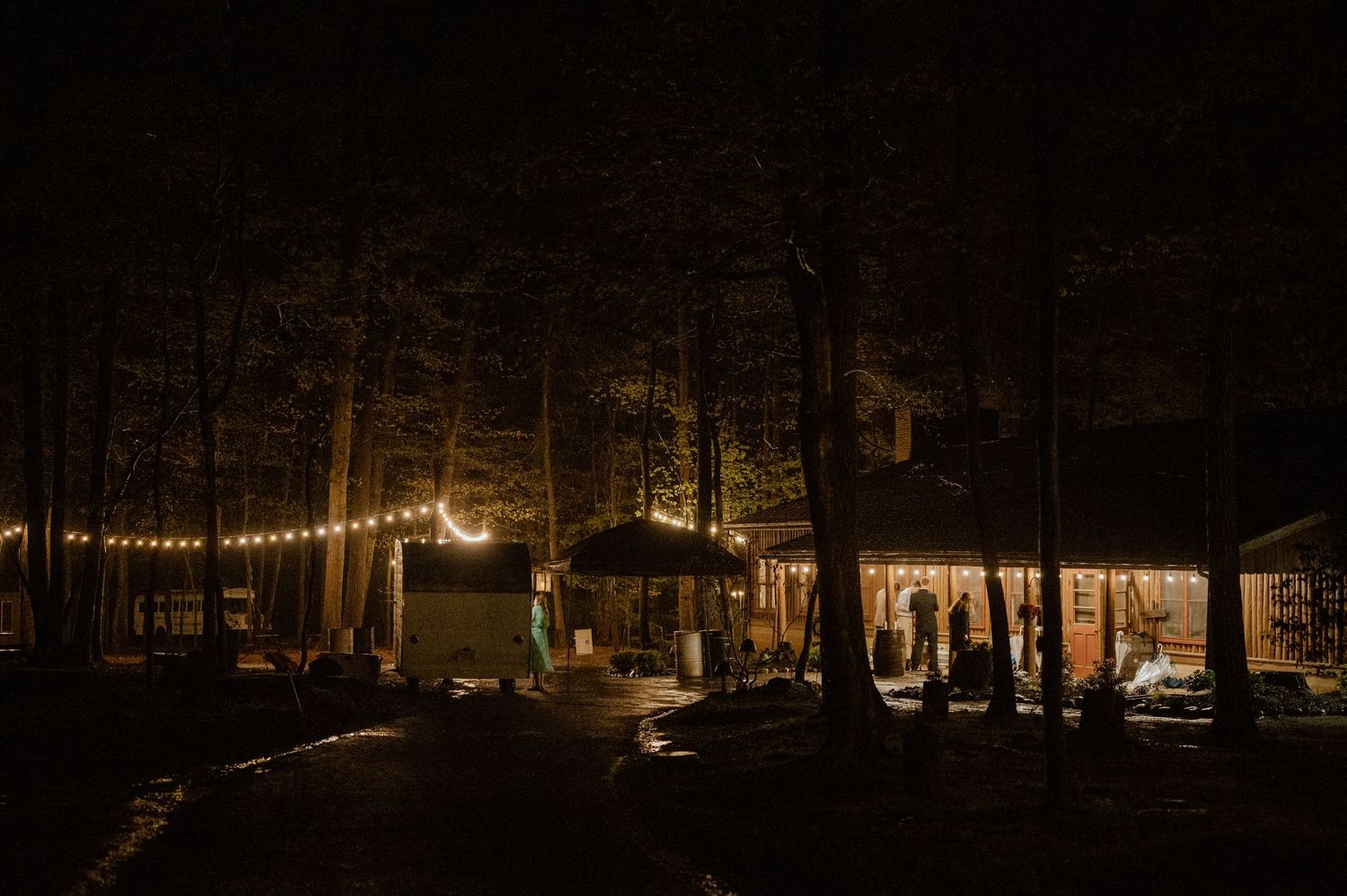 Nighttime exterior view of illuminated venue with string lights and trees.