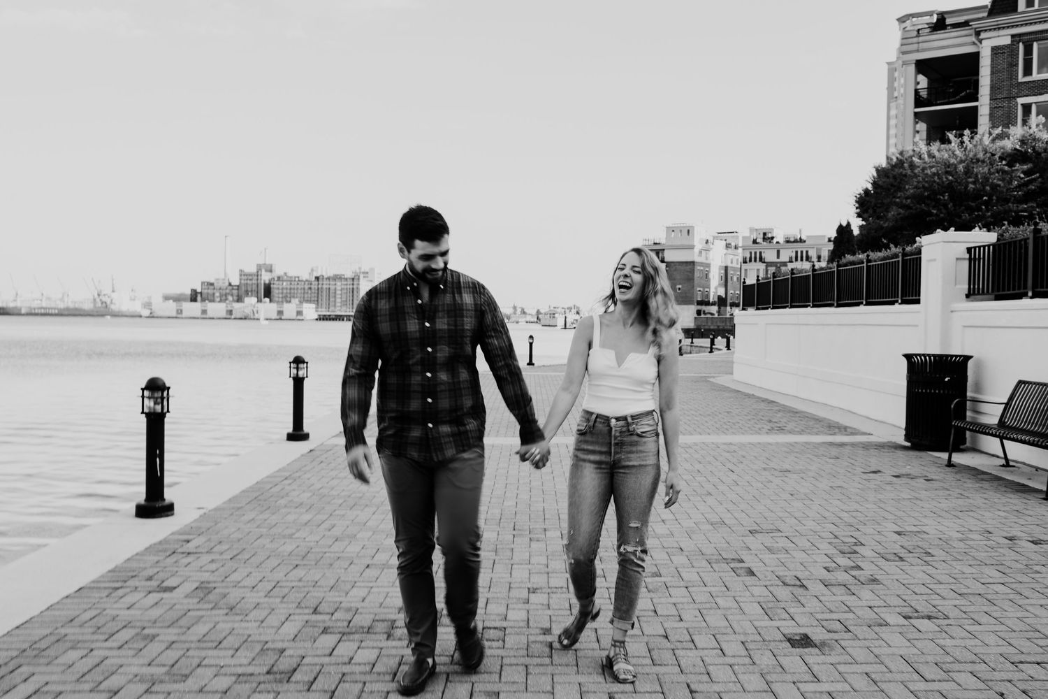 Black and white photo of couple walking along waterfront promenade.