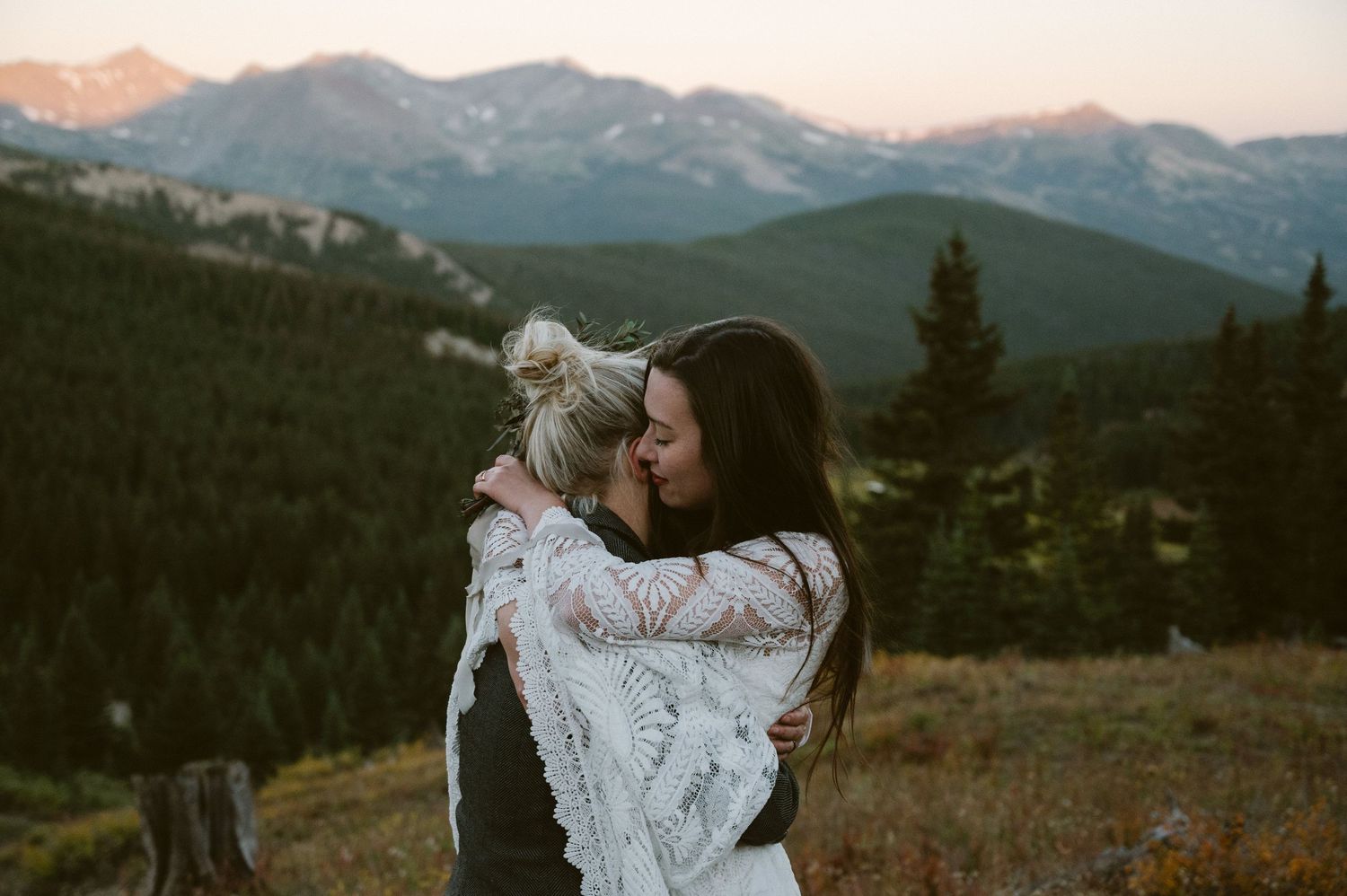 An intimate embrace against a backdrop of snow-capped mountain peaks at sunset.