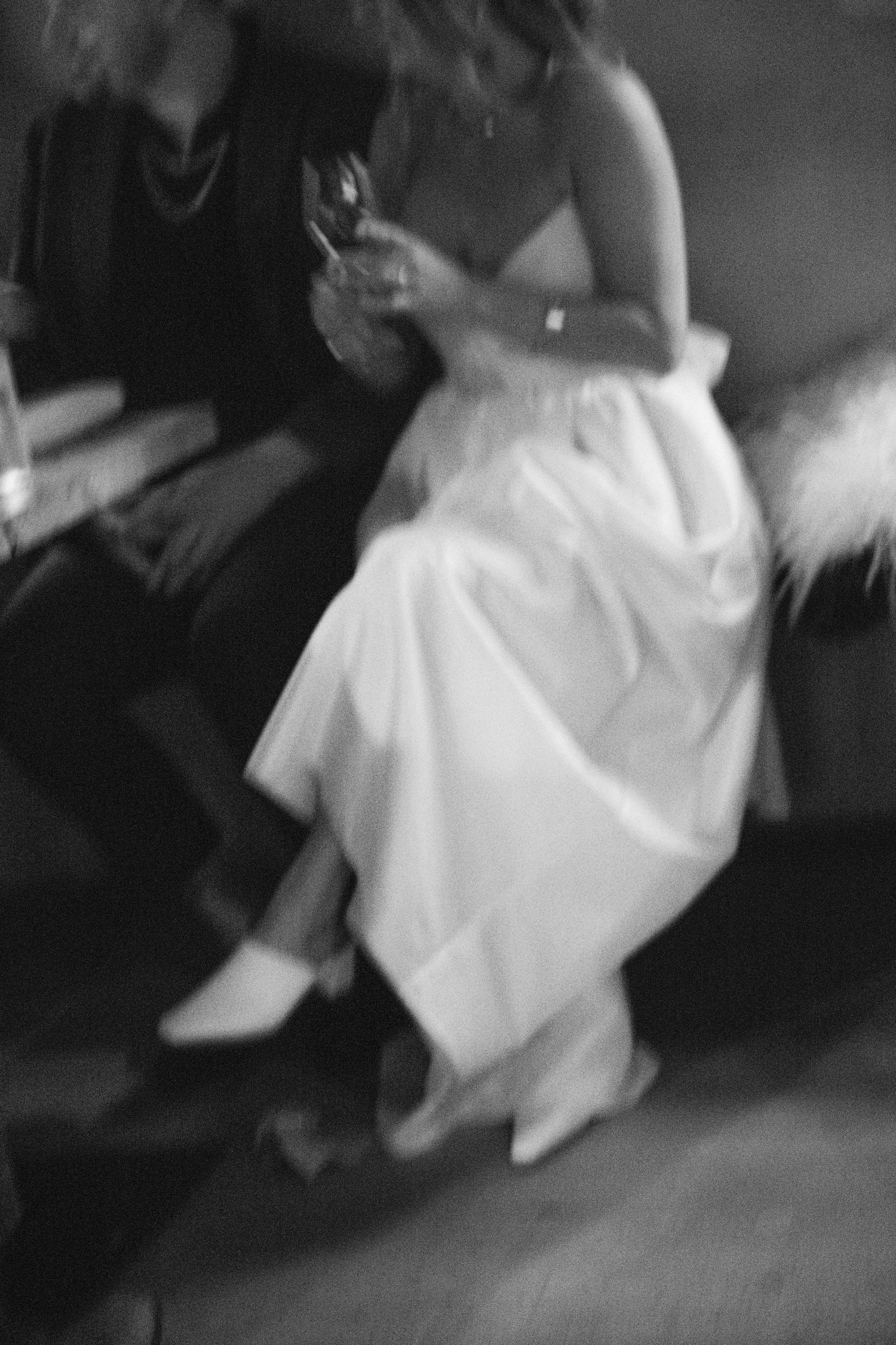 A blurry black and white image of people seated with drinks in formal attire at Fadensonnen in Baltimore