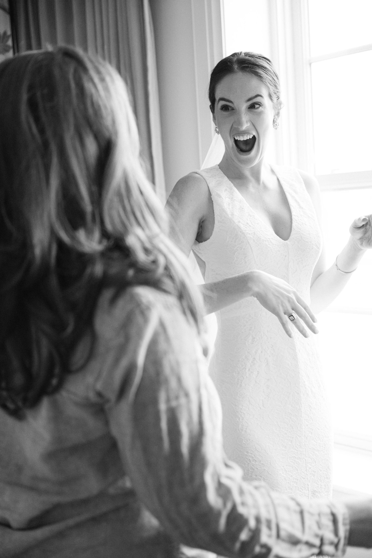 Joyful moment captured in black and white as a person in a wedding dress expresses excitement.