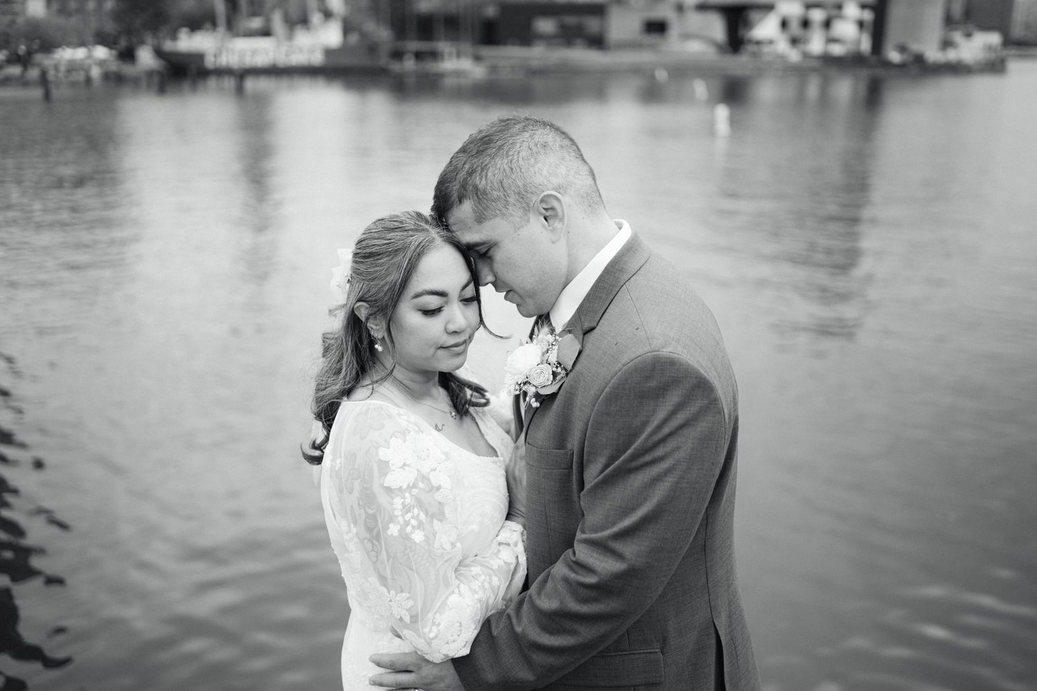 Black and white romantic waterfront portrait of newlyweds sharing an intimate moment with a tranquil lake in the background.