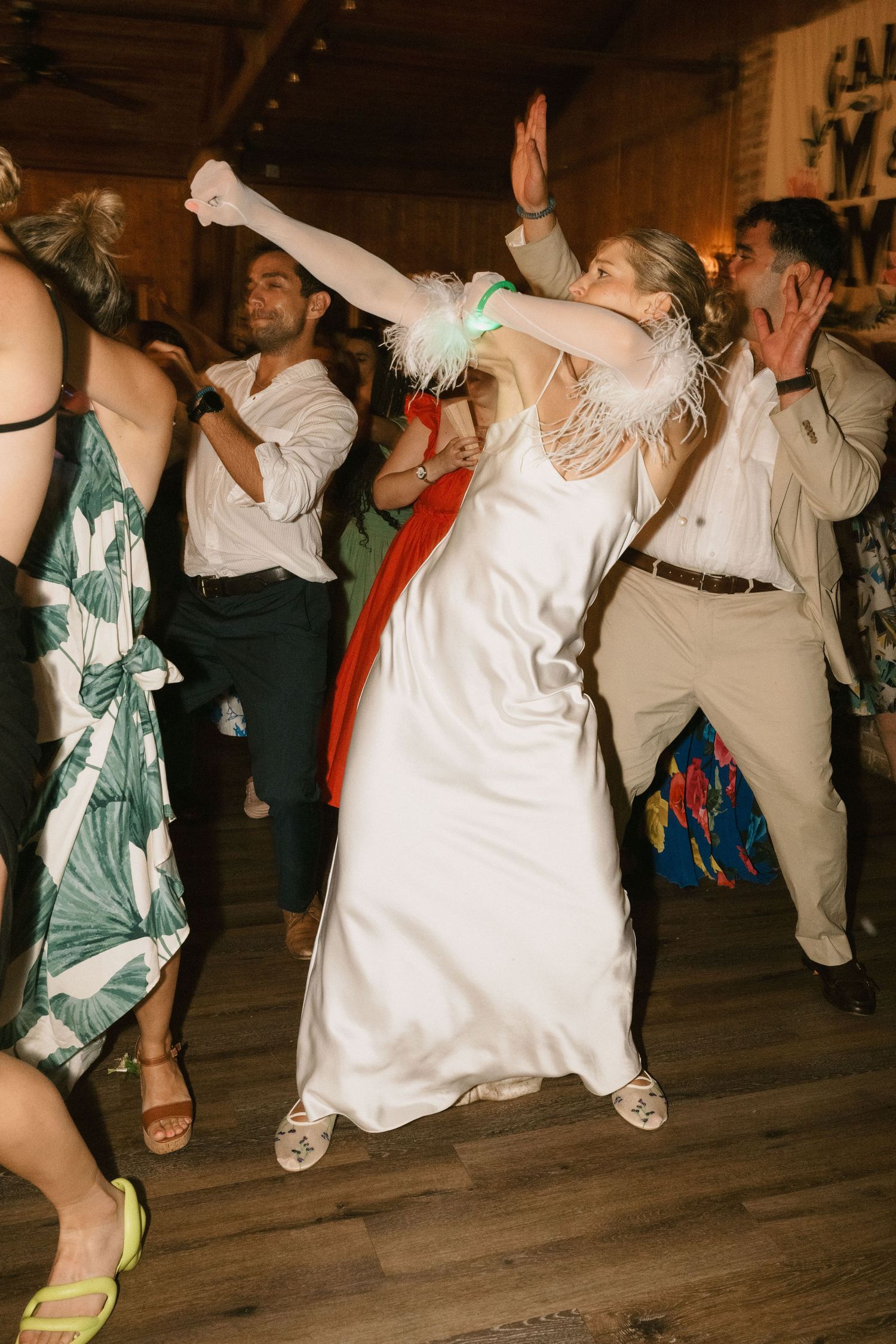 Energetic dancing at a celebration with guests in formal attire on wooden floor.