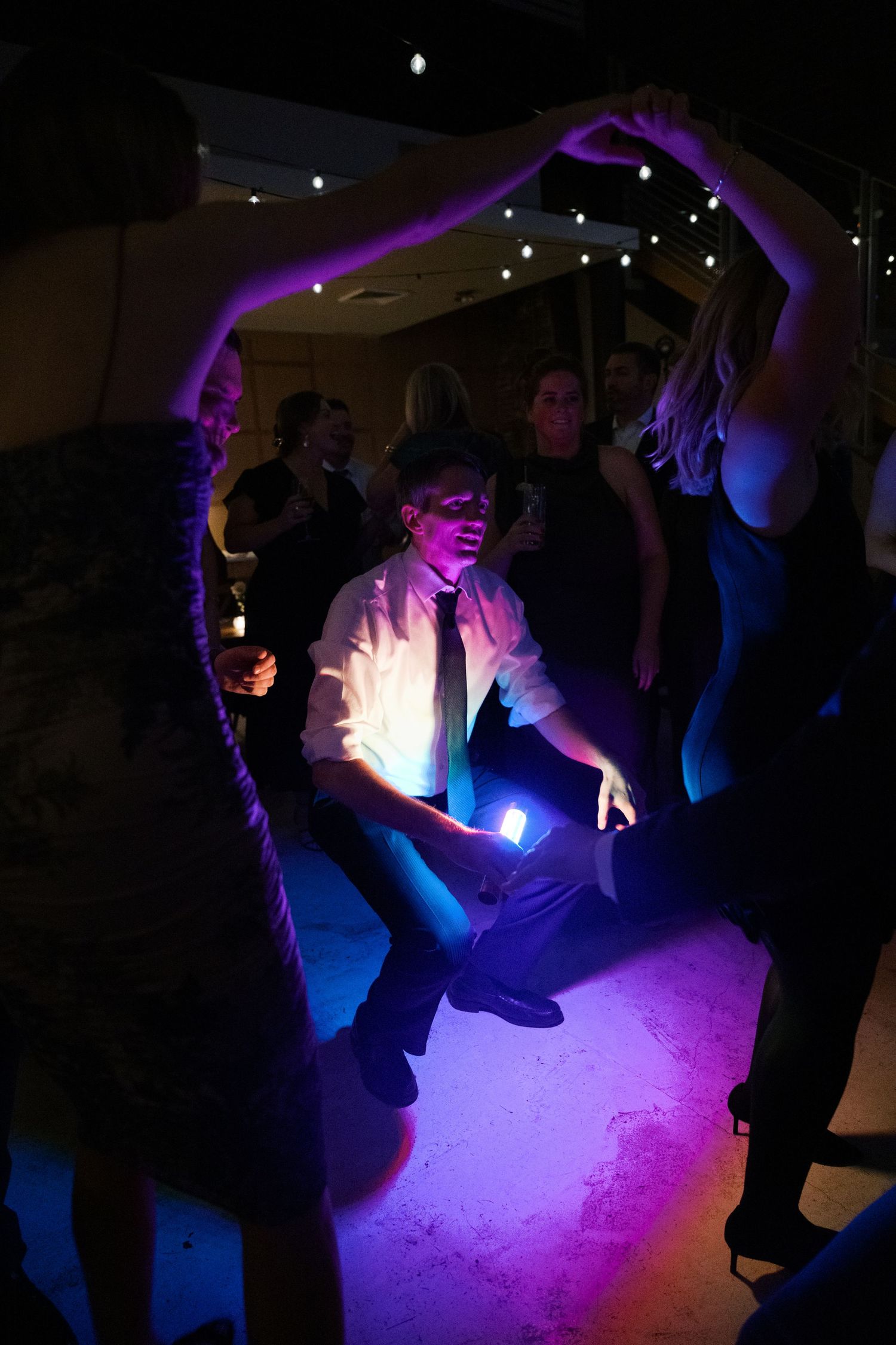 Dancers silhouetted against purple and blue lighting on a dark dance floor.