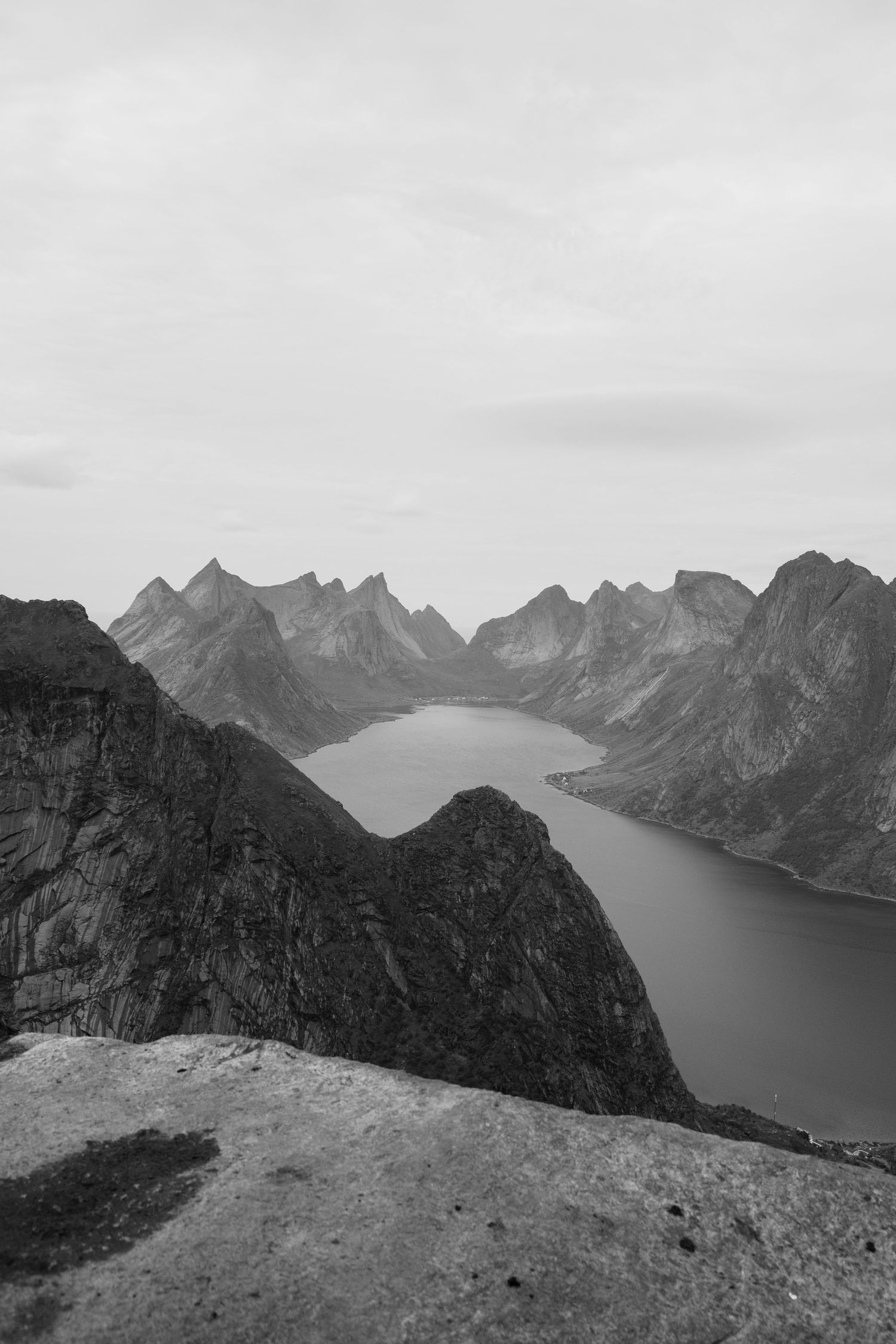 Black and white photograph of a majestic Norwegian fjord surrounded by steep mountain ranges.