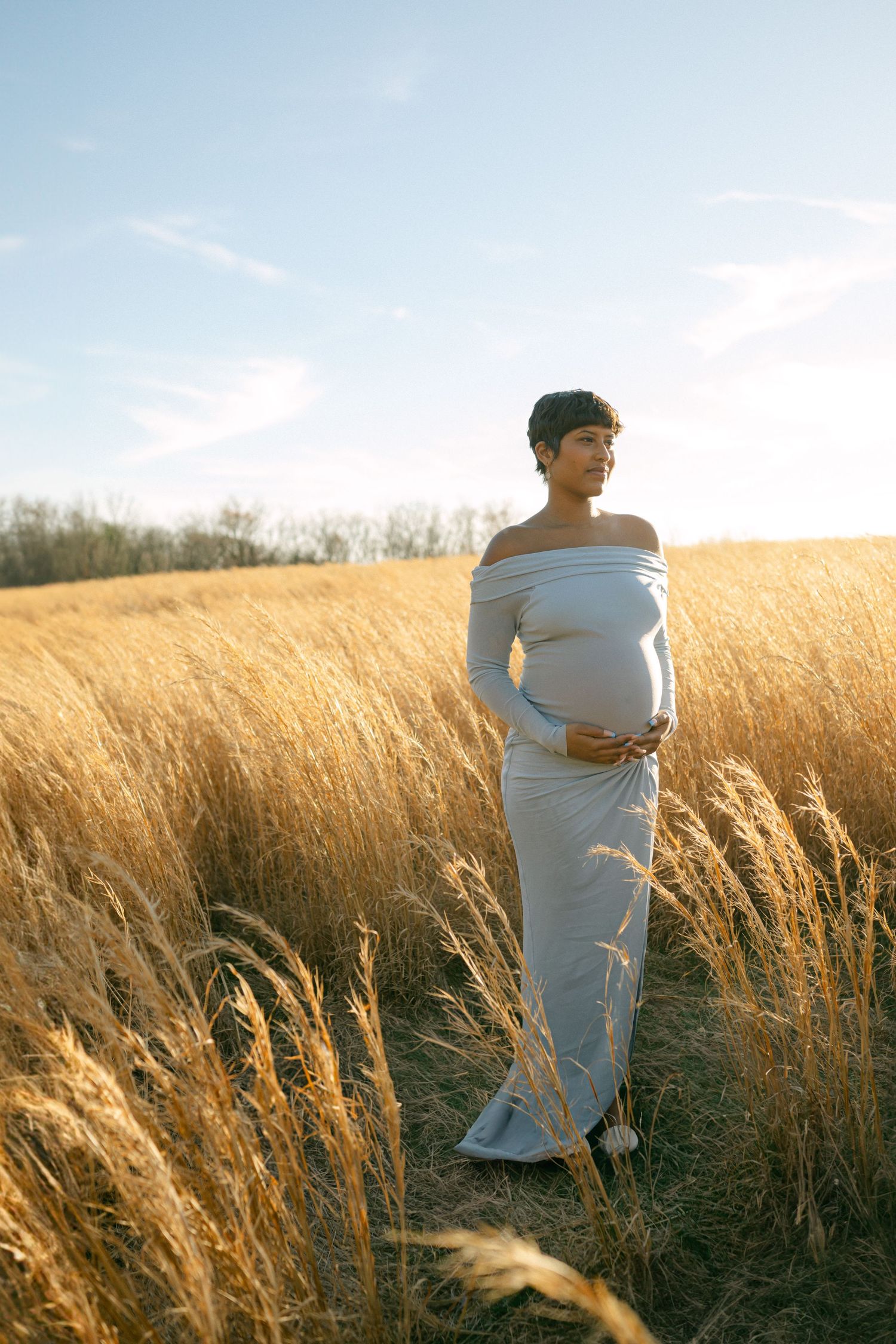 maternity photo of woman holding baby bump in field