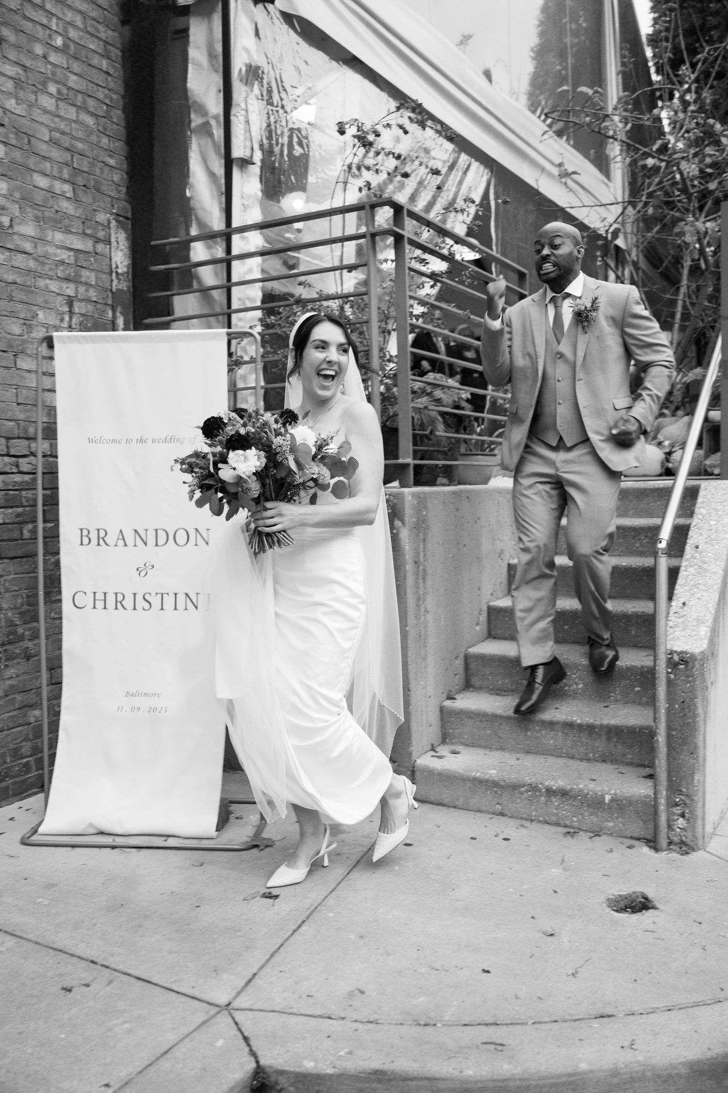 Wedding celebration outside brick building with shopping bags and festive atmosphere.