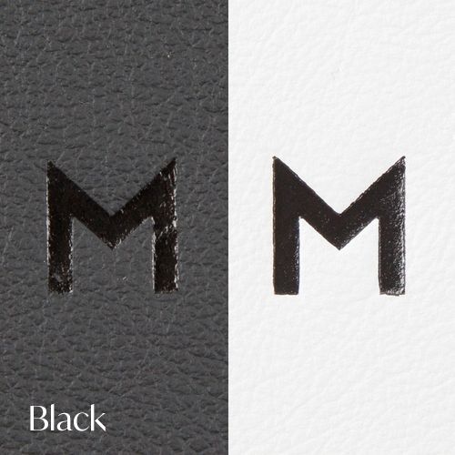 The letter M shown in black finish on dark leather and white backgrounds.