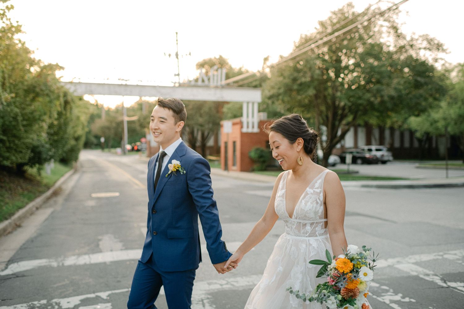 bride and groom laugh as they cross street