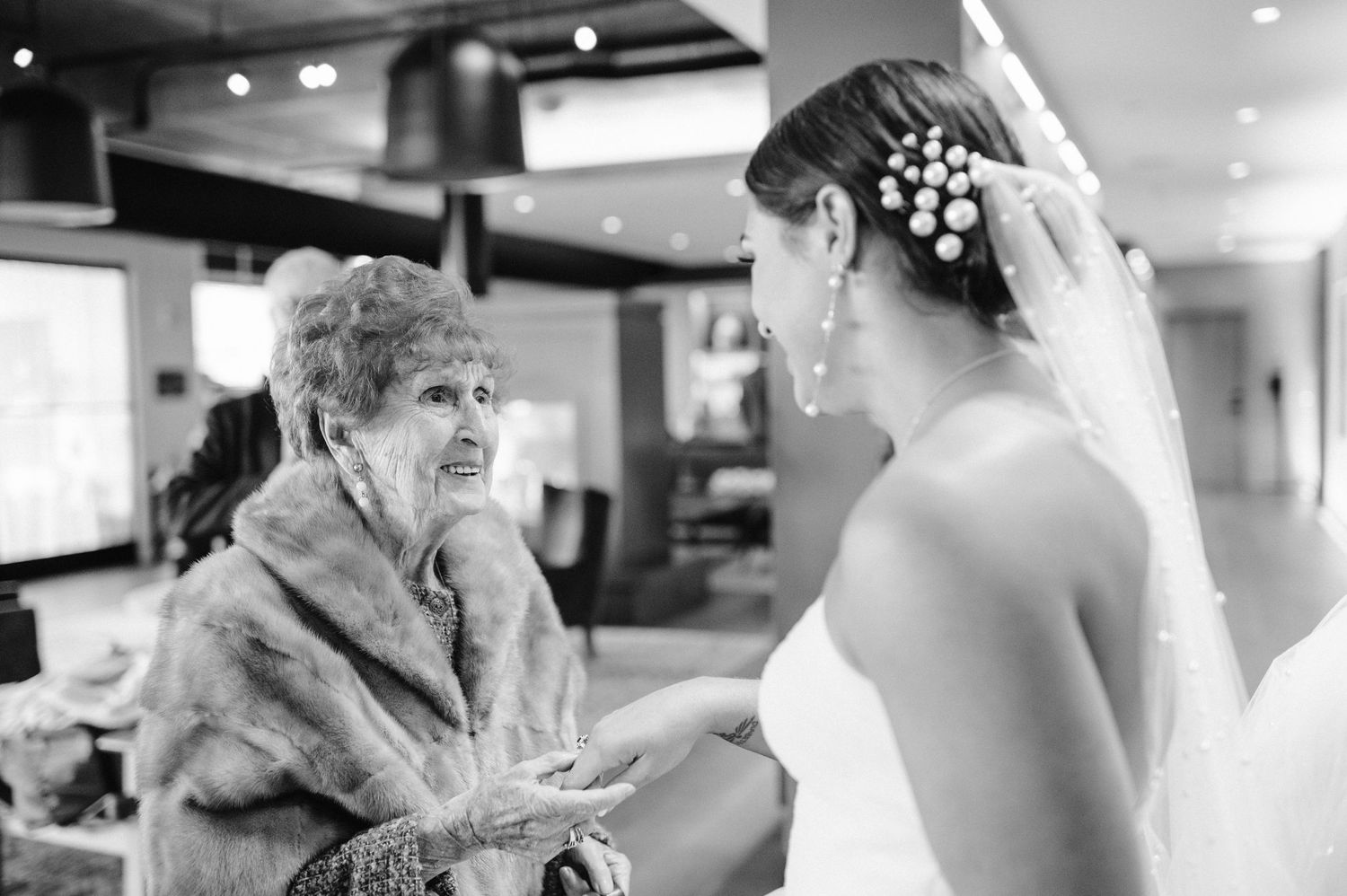 An emotional moment shared between a bride and an elderly woman in a fur coat.