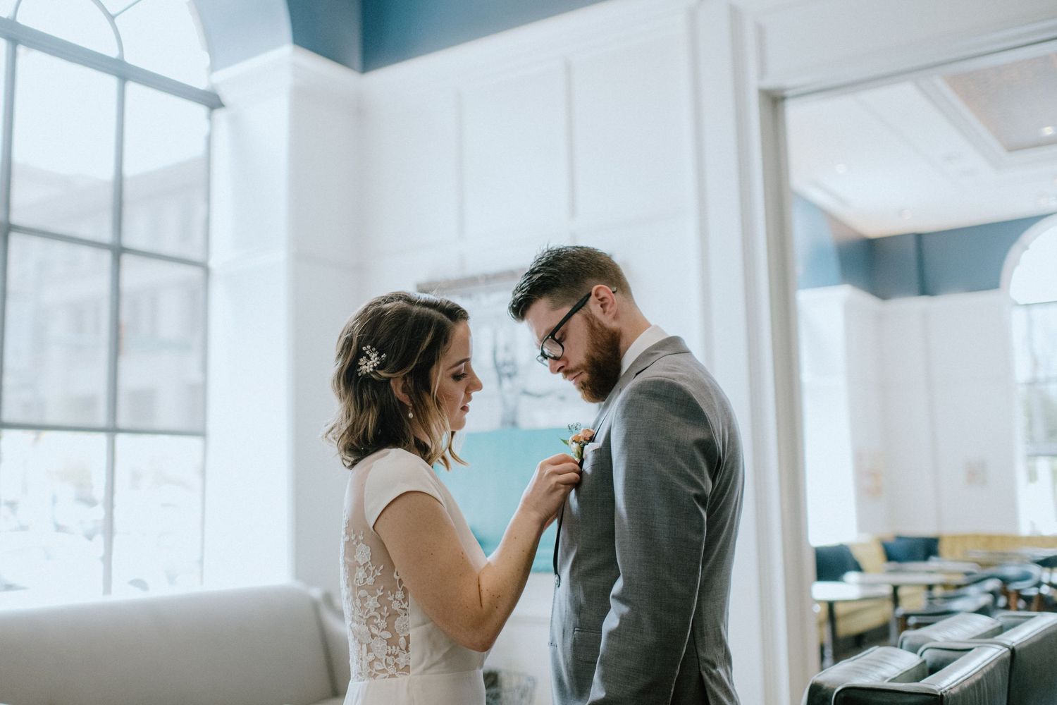 bride pins boutonniere on groom