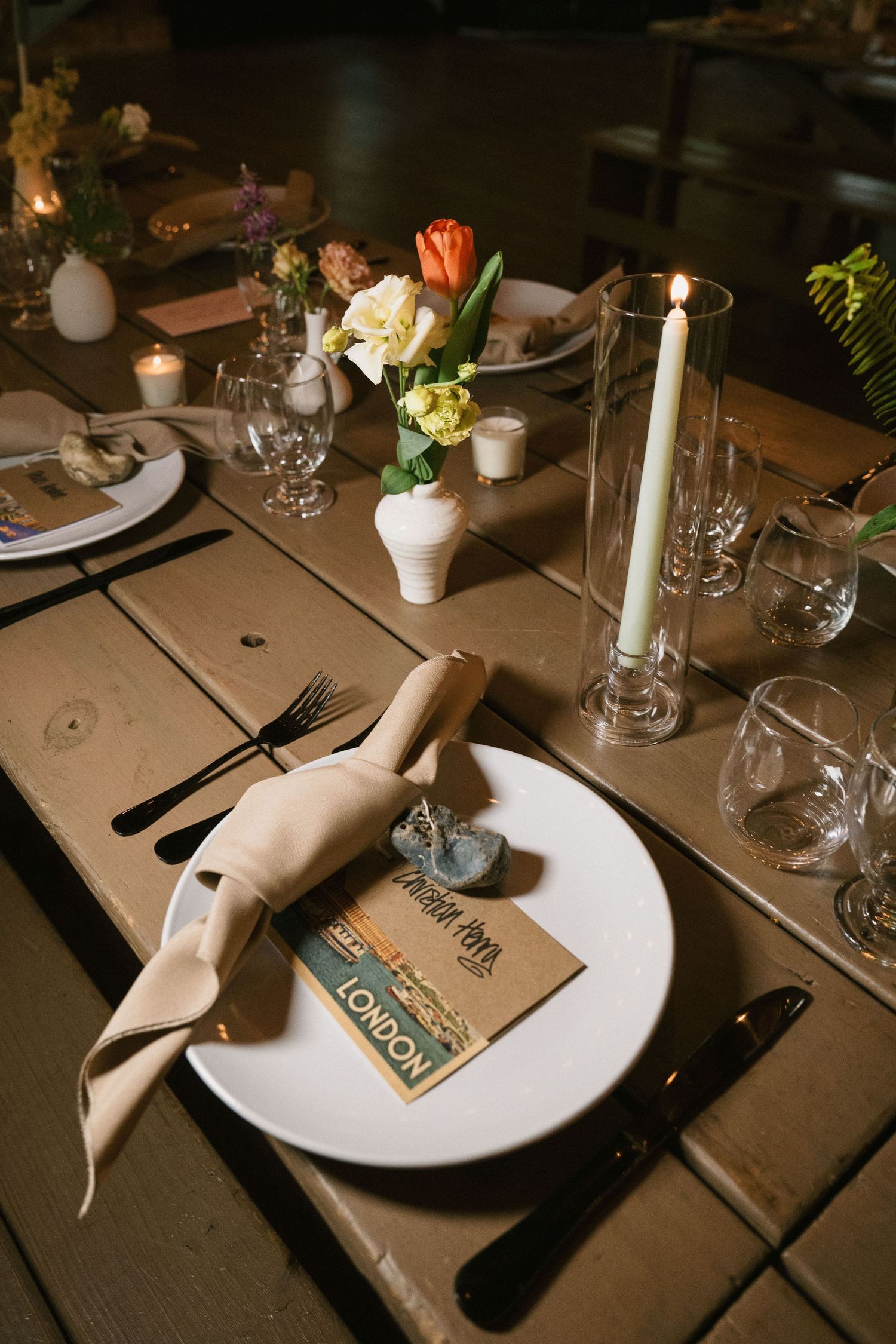 Elegant table setting with candles, flowers and place settings at a wedding reception.
