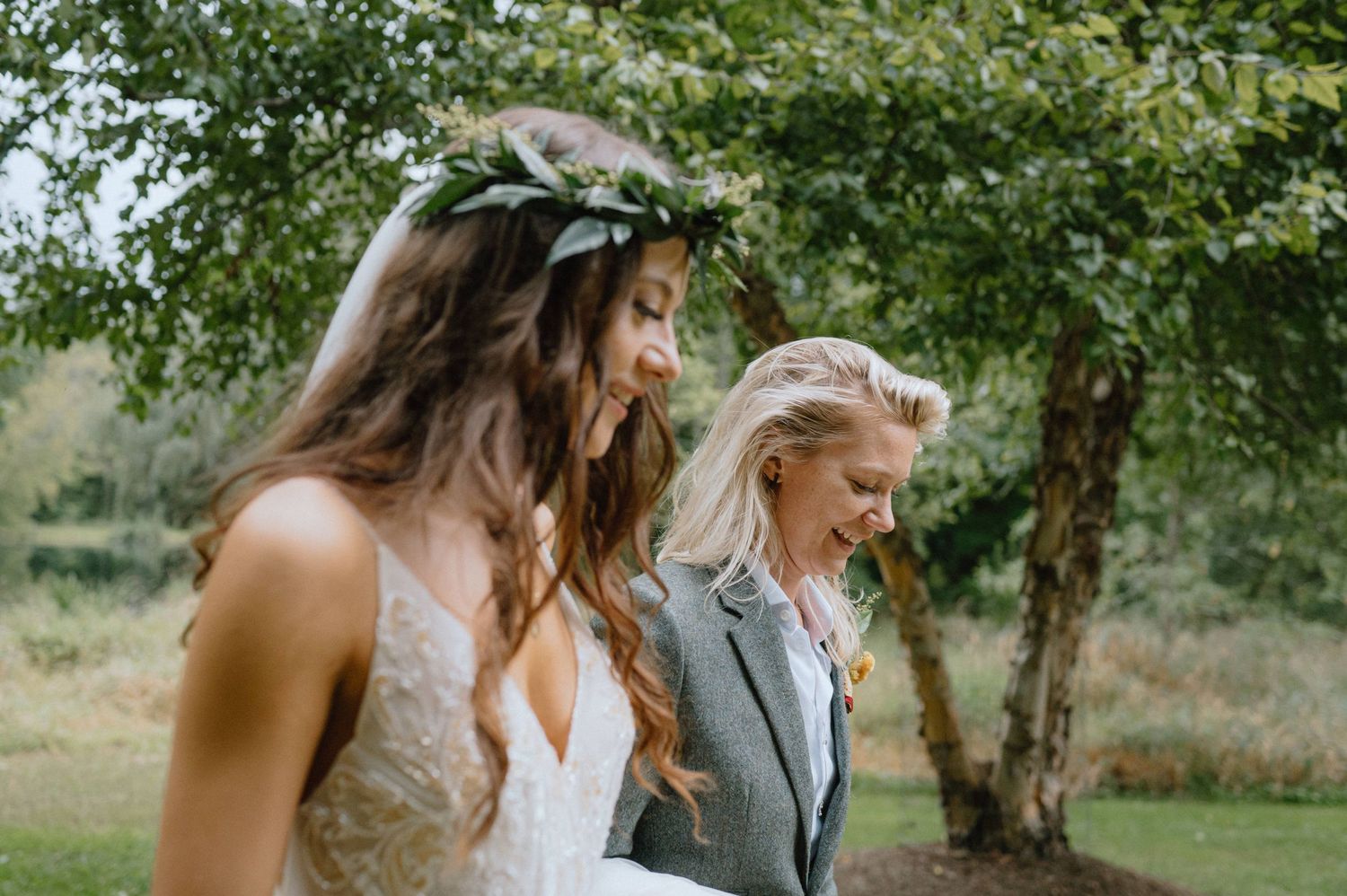 A candid wedding moment captured in a natural outdoor setting with soft lighting.
