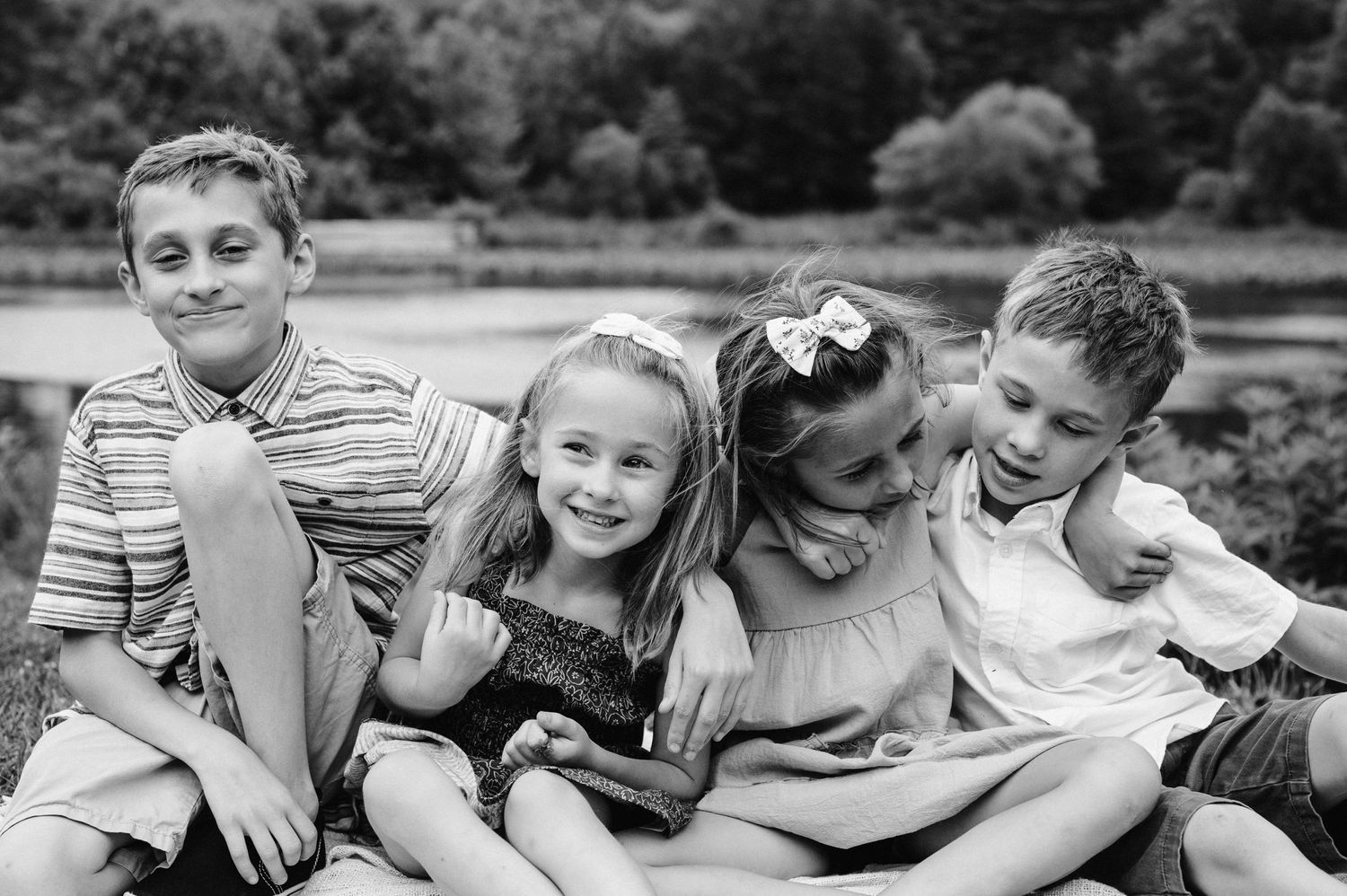 Children sitting close together outdoors sharing laughs and smiles.
