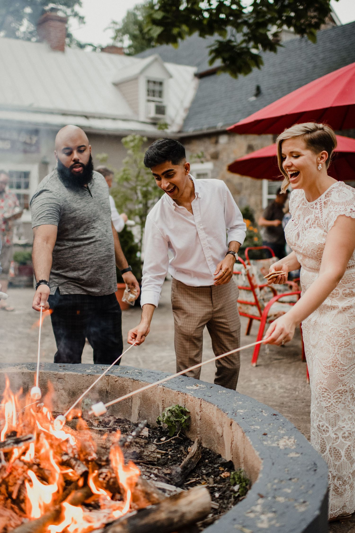 People roast marshmallows over a large outdoor fire pit during a celebration.