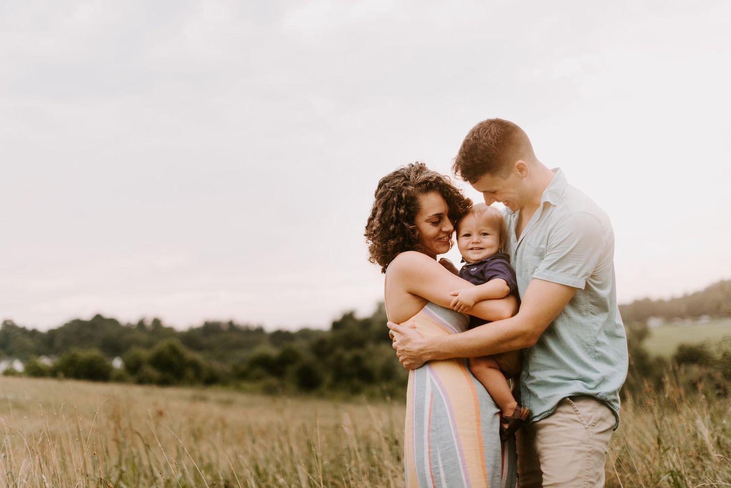 Intimate family embrace in a golden field during sunset.