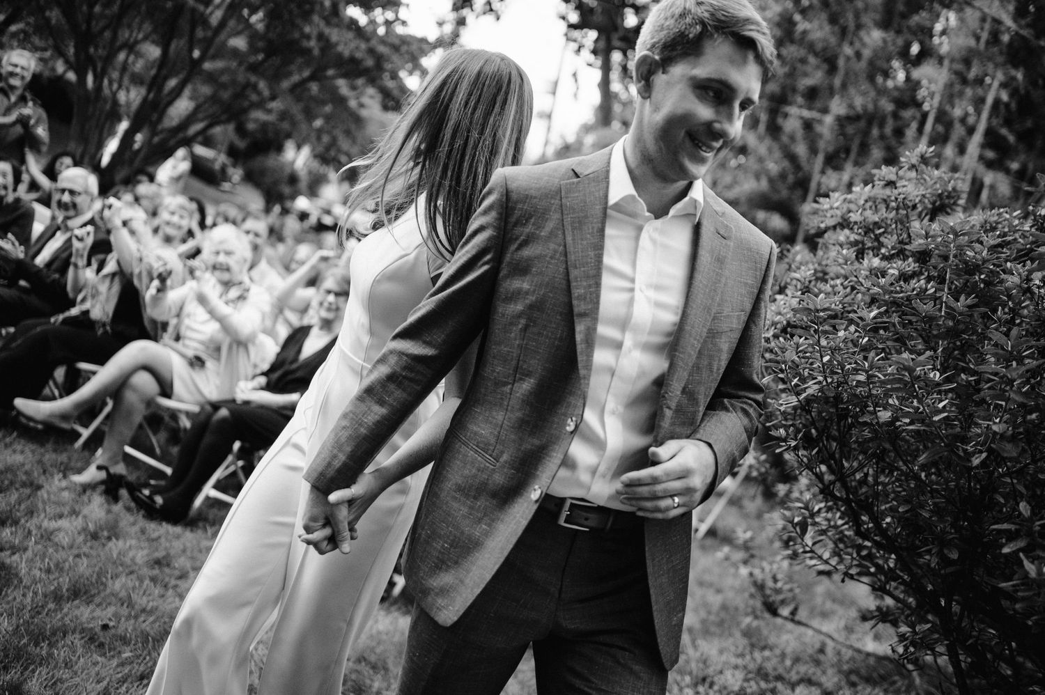 Black and white candid moment from outdoor garden wedding ceremony.