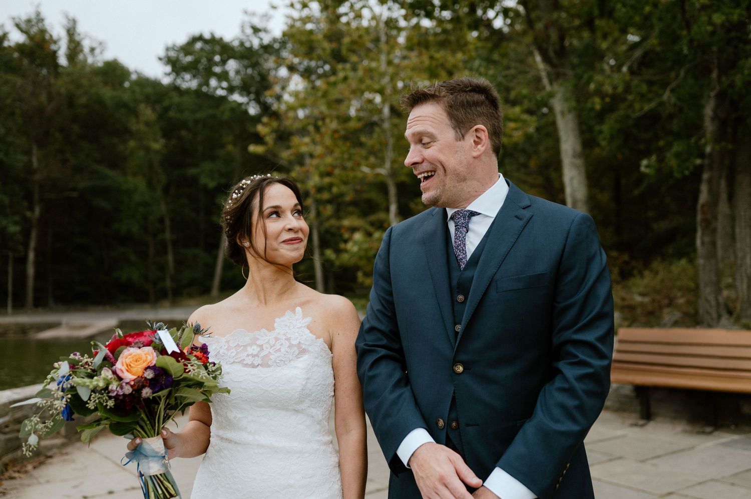 A couple shares a candid moment together outdoors with a colorful bouquet.