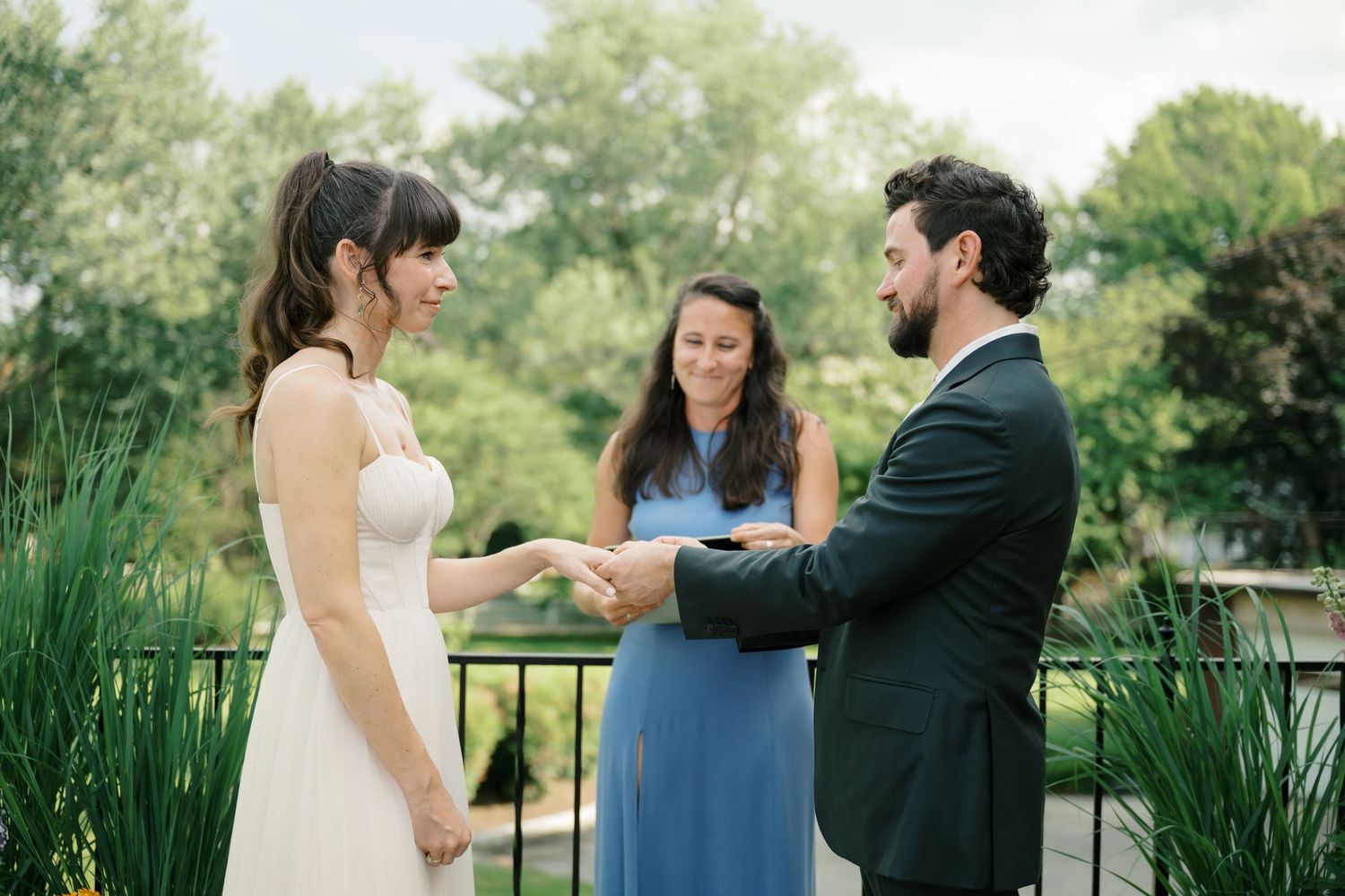 Wedding ceremony unfolds in a scenic outdoor garden with vibrant summer foliage.