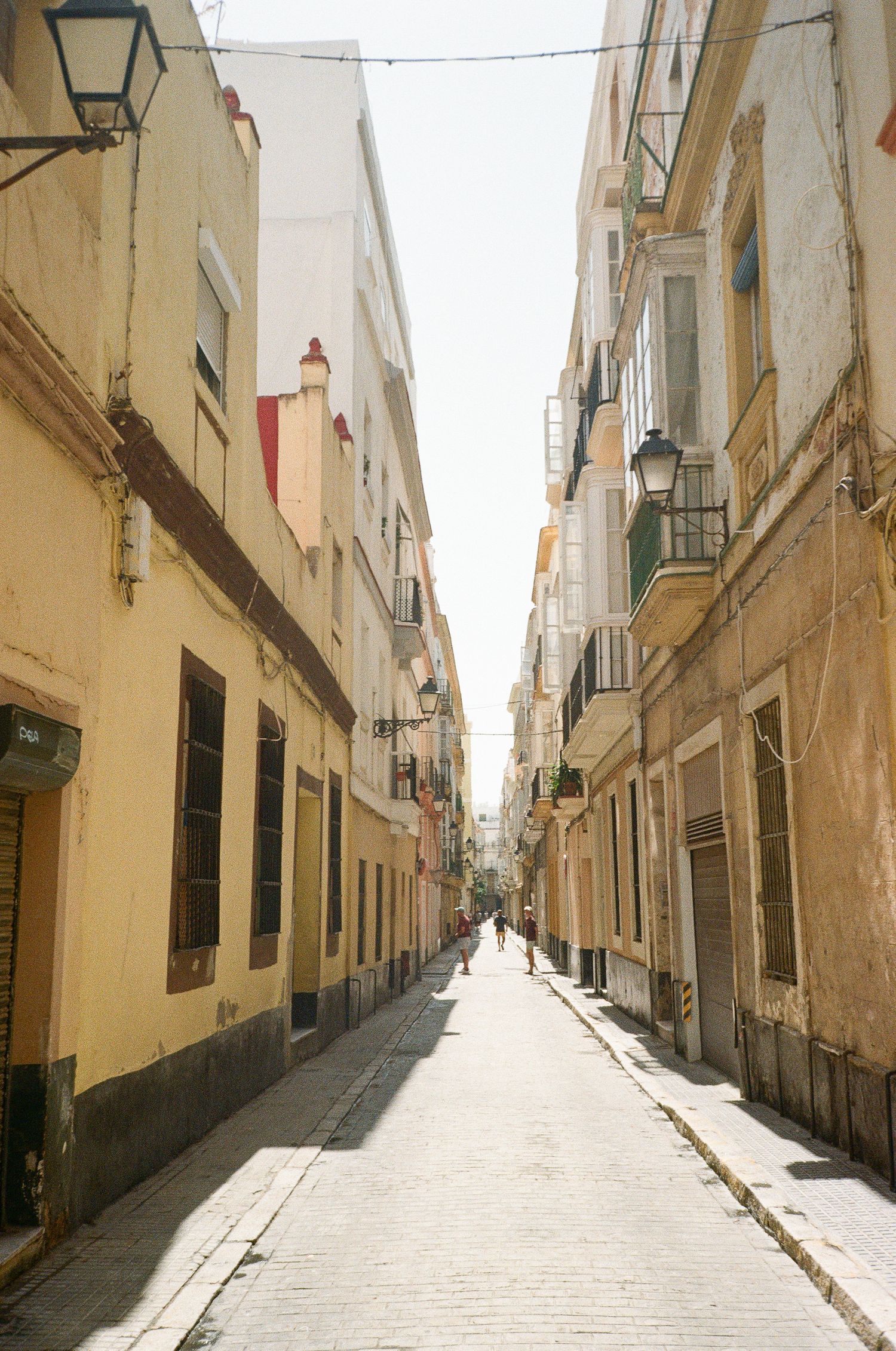 Narrow cobblestone alley between old beige buildings leading to a distant vanishing point.