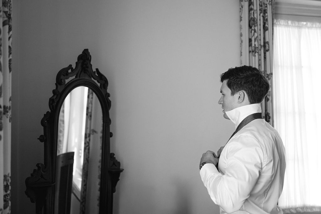 Black and white portrait series showing wedding day preparation in front of a mirror.