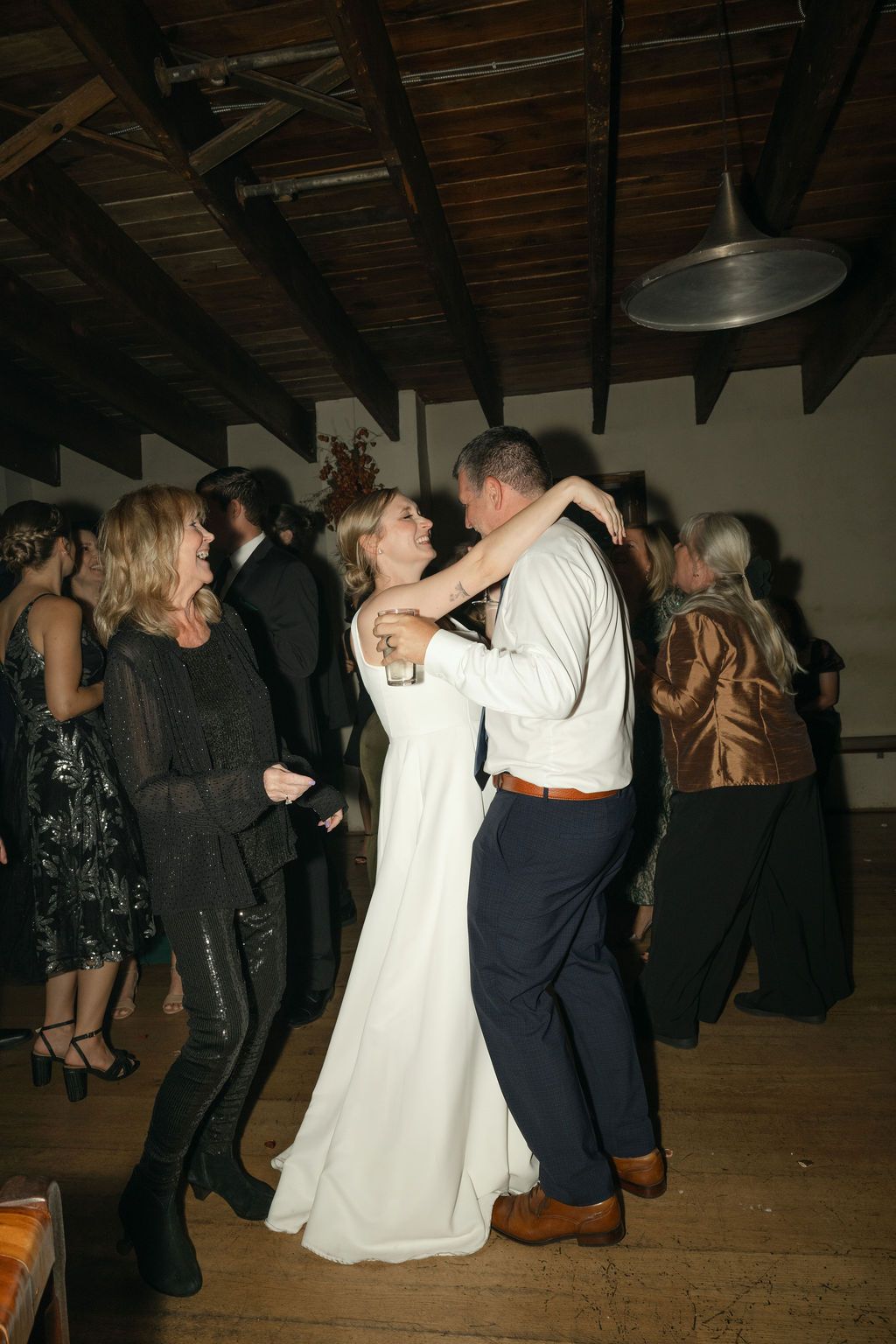 Couples slow dancing on a wooden floor under rustic beamed ceiling at a wedding reception at Fadensonnon in Baltimore