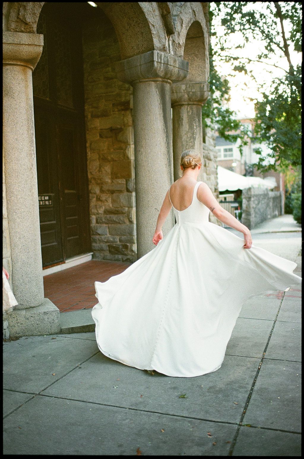 A bride twirls in her flowing white dress under historic stone archways.