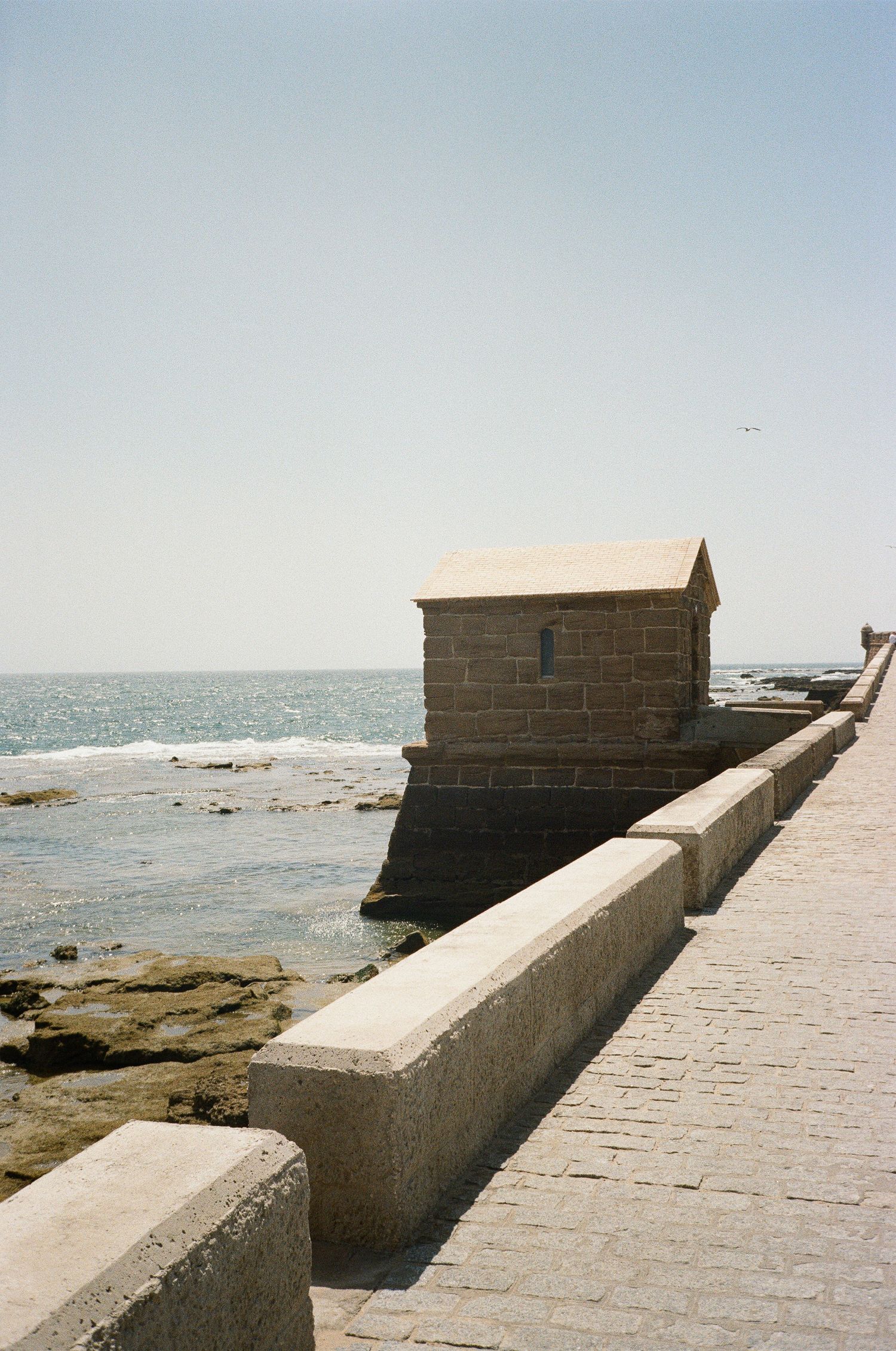 Stone fortification wall with small buildings stretches along the coastline.
