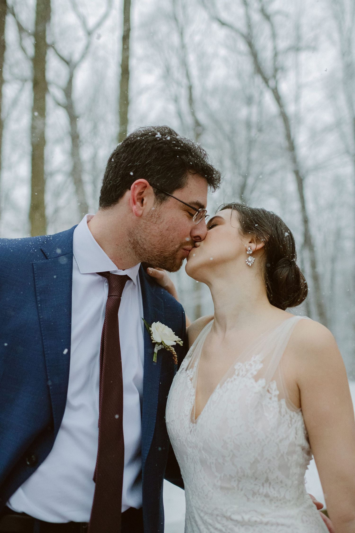 An intimate winter wedding portrait with snow falling in the background.