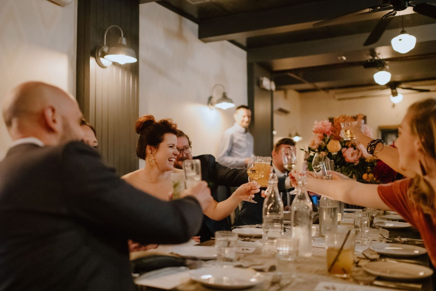 Wedding guests raising glasses in a toast during reception dinner.