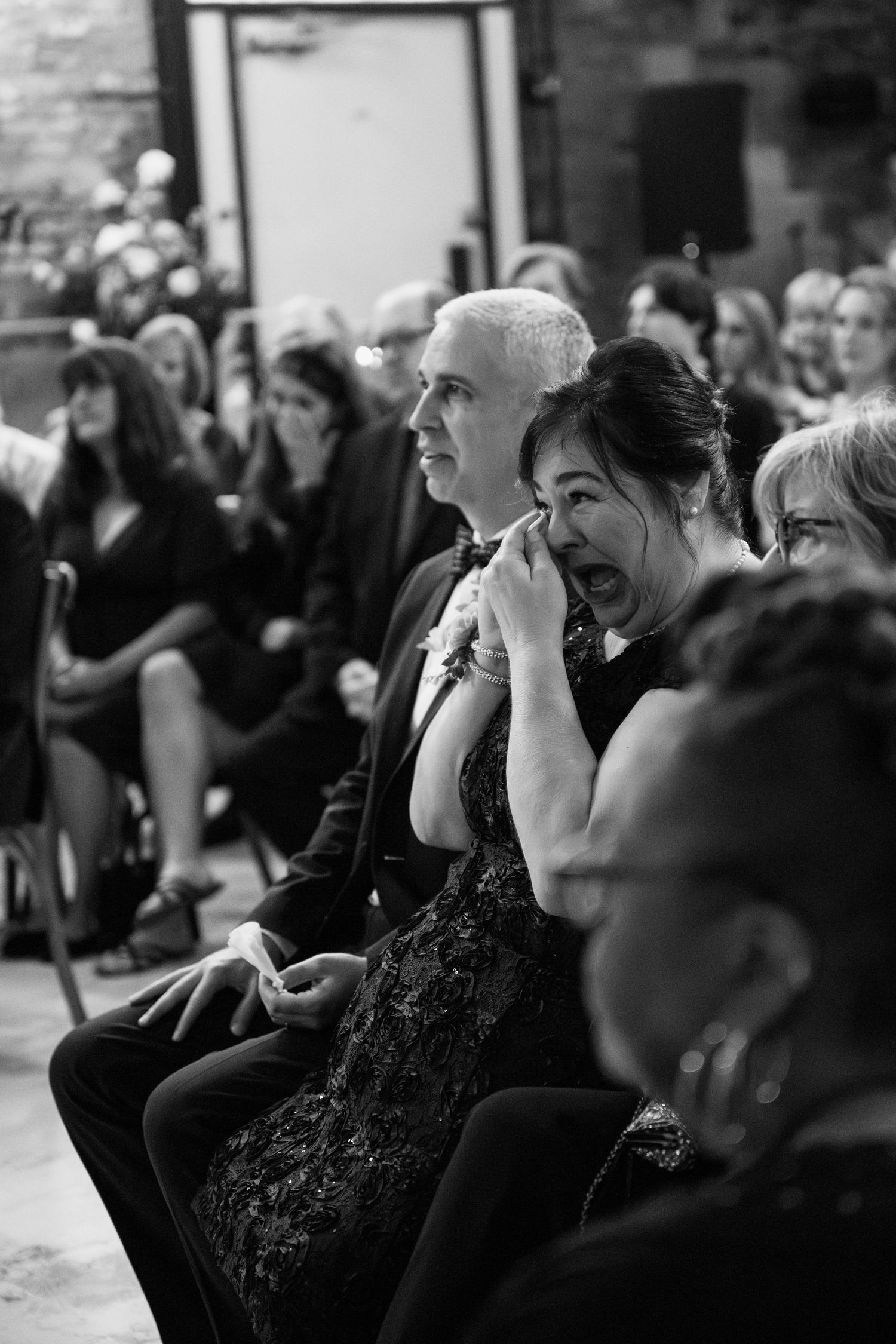 Black and white photo of wedding guests showing emotional reactions during ceremony.